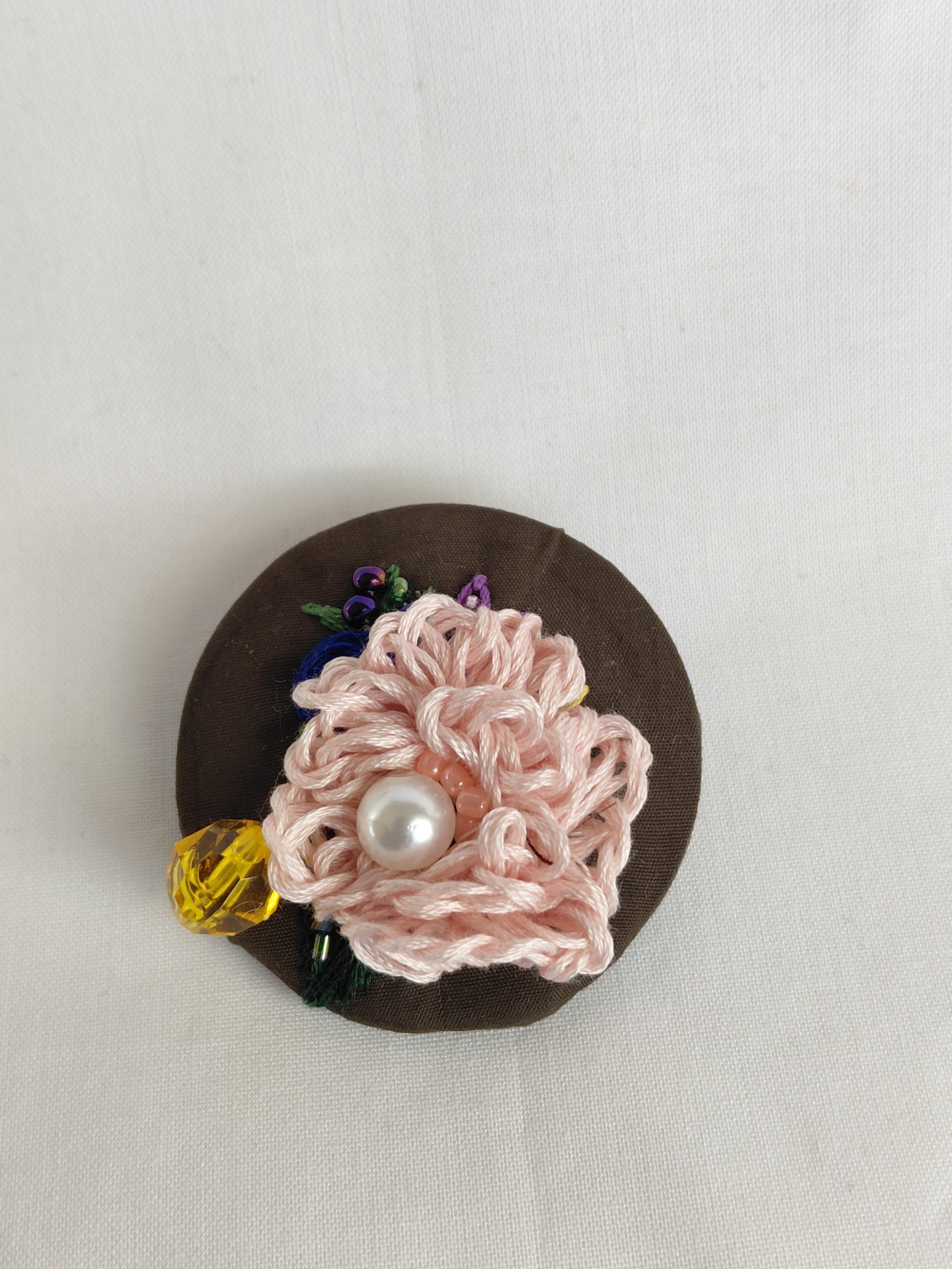 Decorative pink flower brooch on olive background