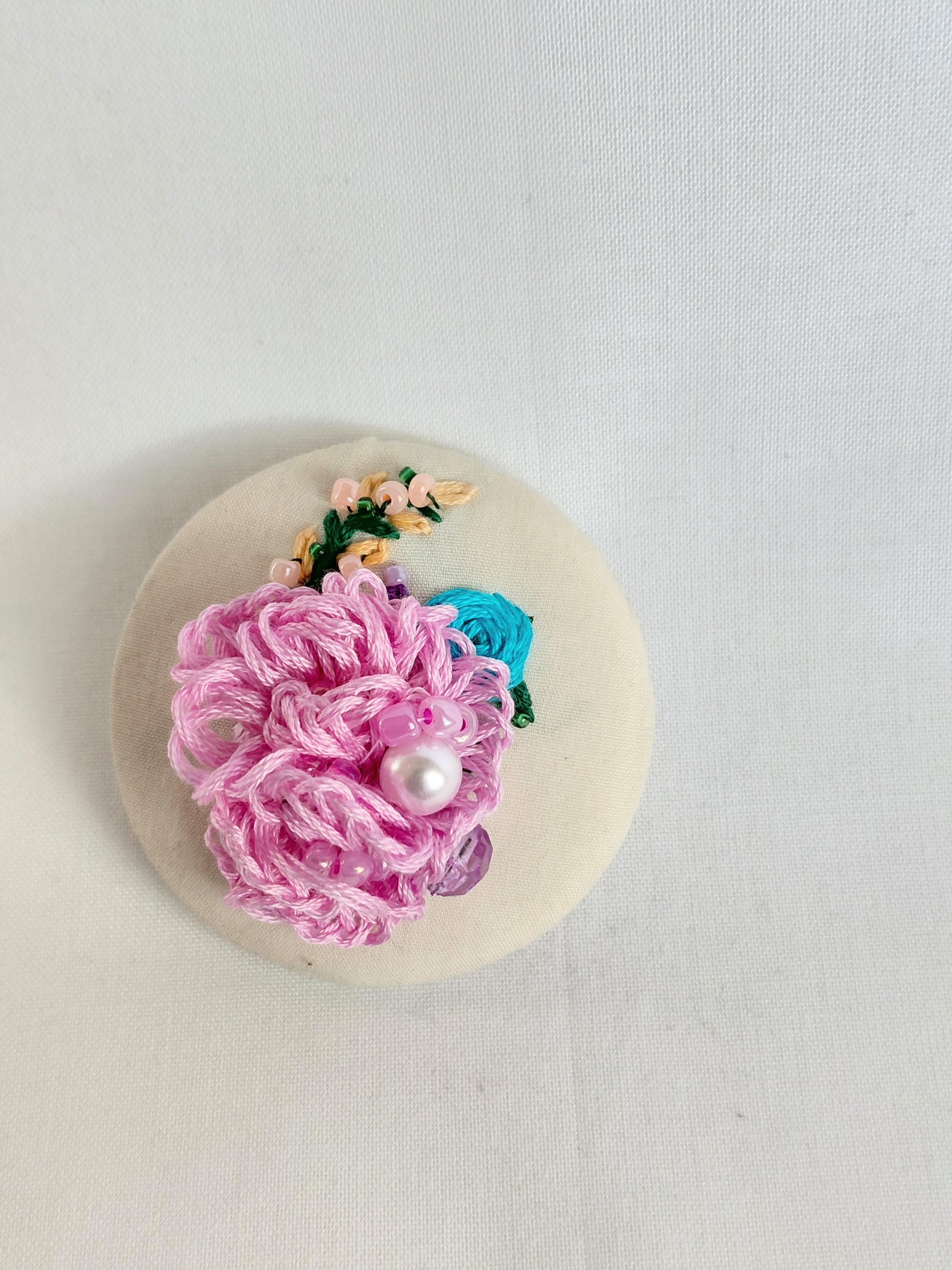 Decorative pink flower brooch on cream background