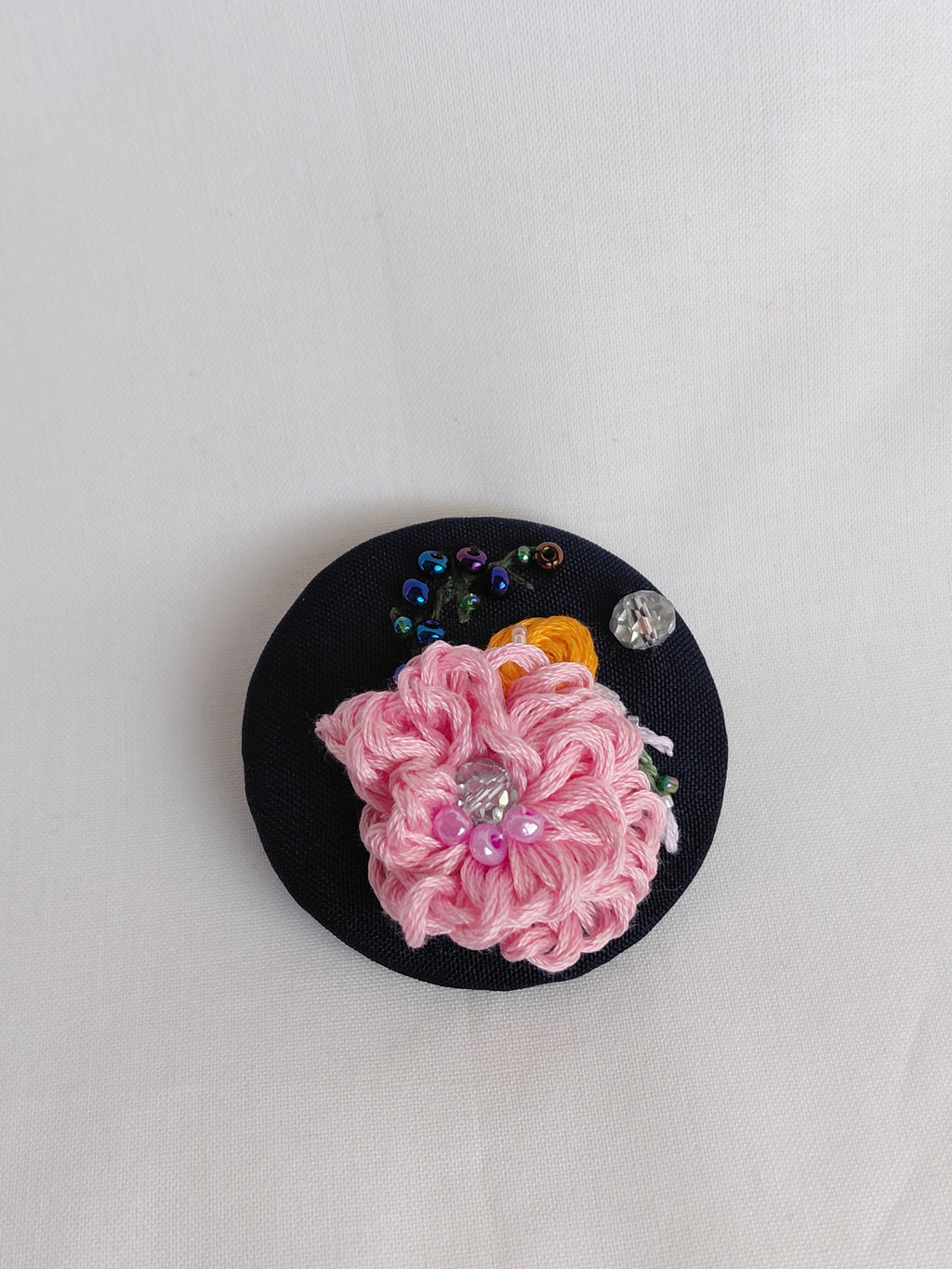 Decorative pink flower brooch on black background