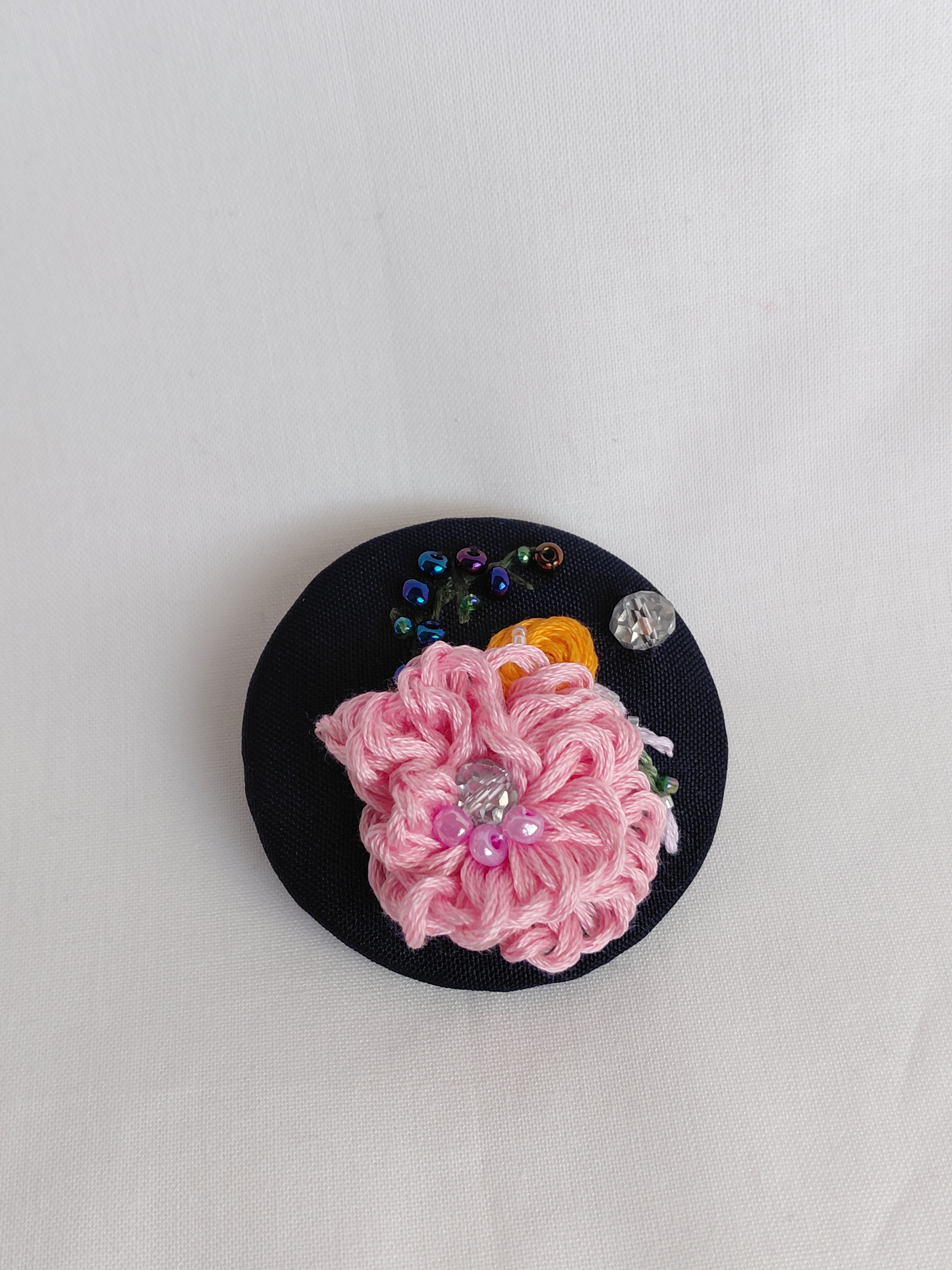 Decorative pink flower brooch on black background