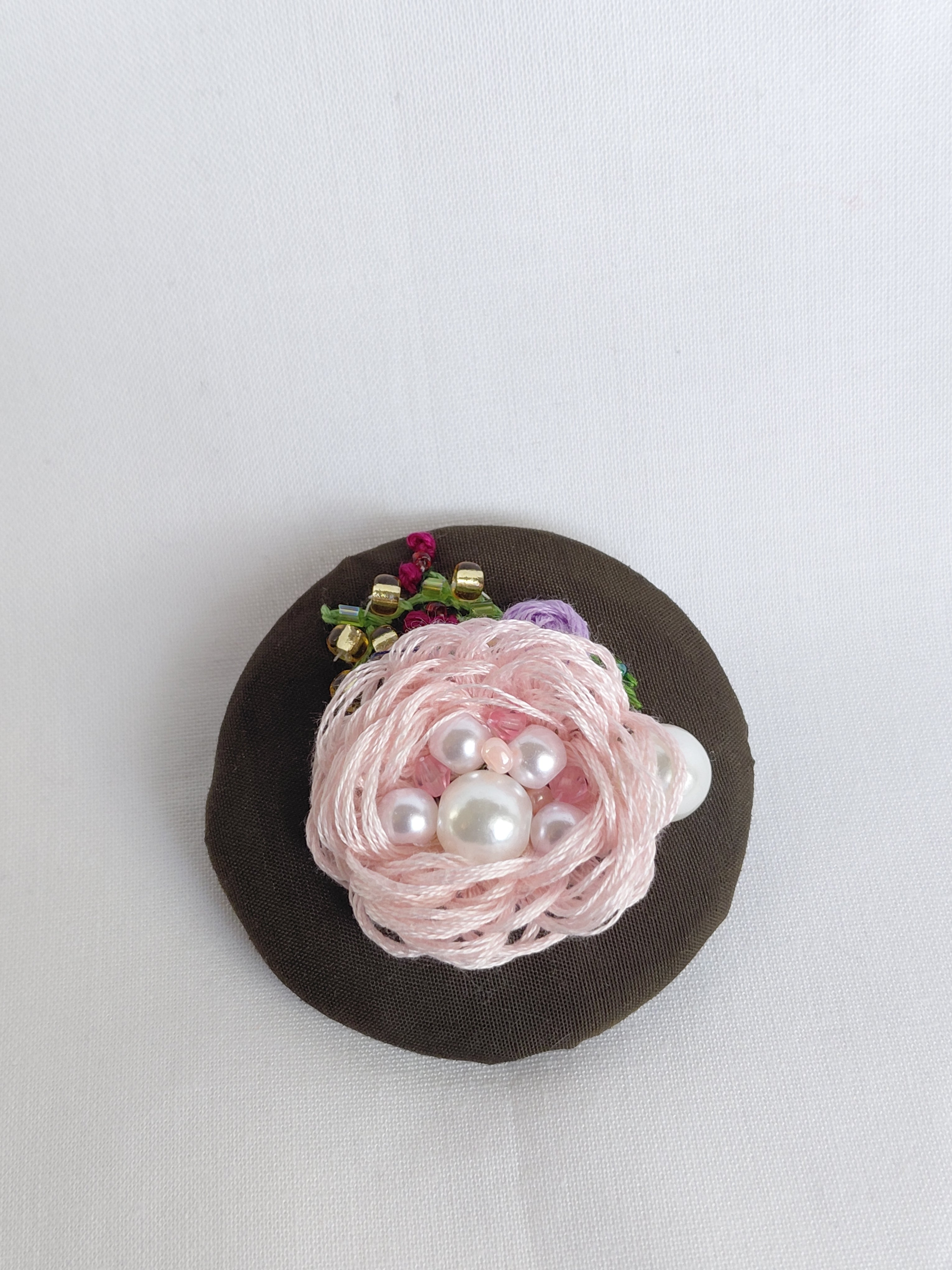 Decorative pink flower brooch on olive background