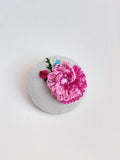 Decorative pink flower brooch on grey background
