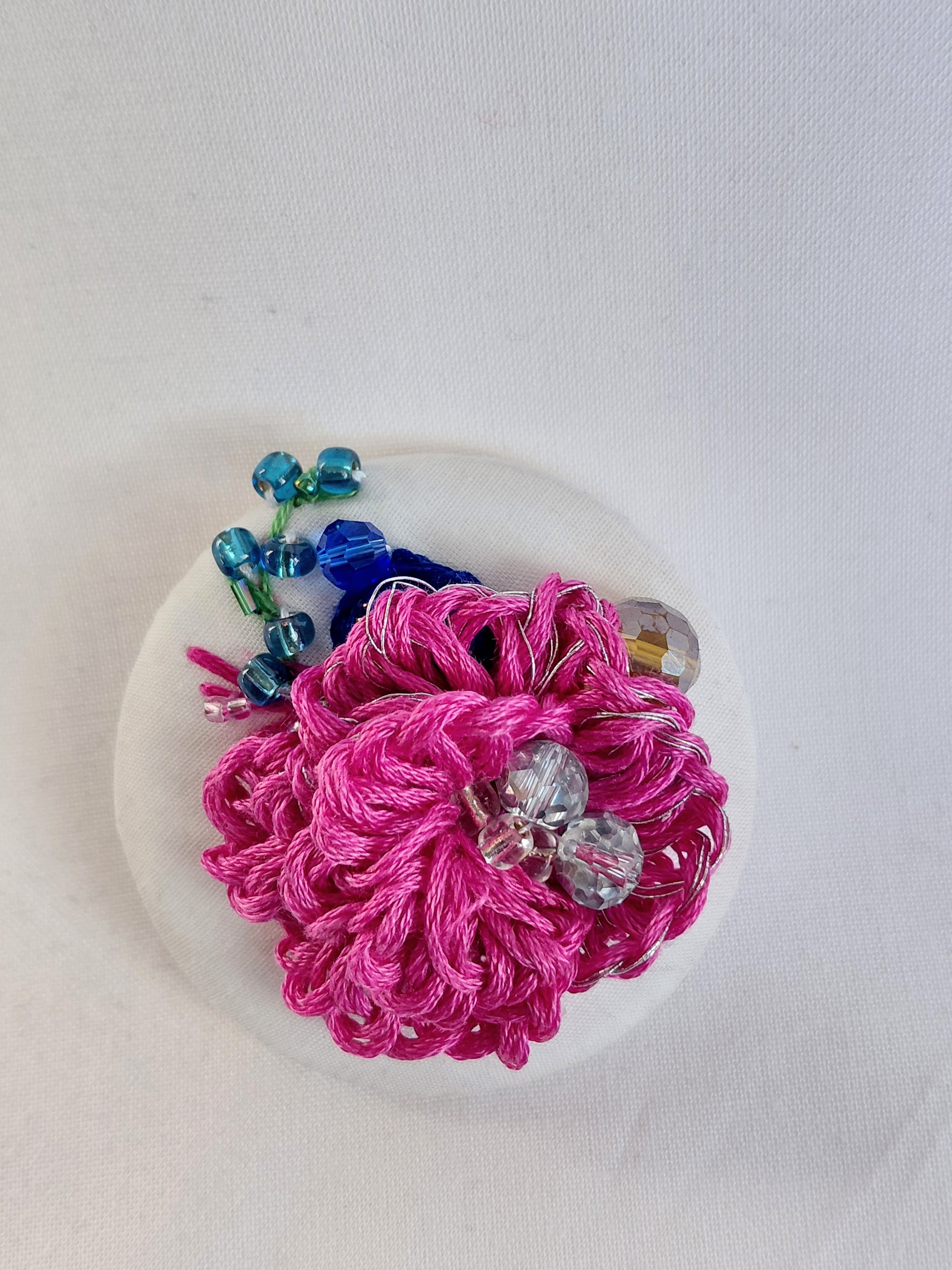Decorative fuschia flower brooch on white background
