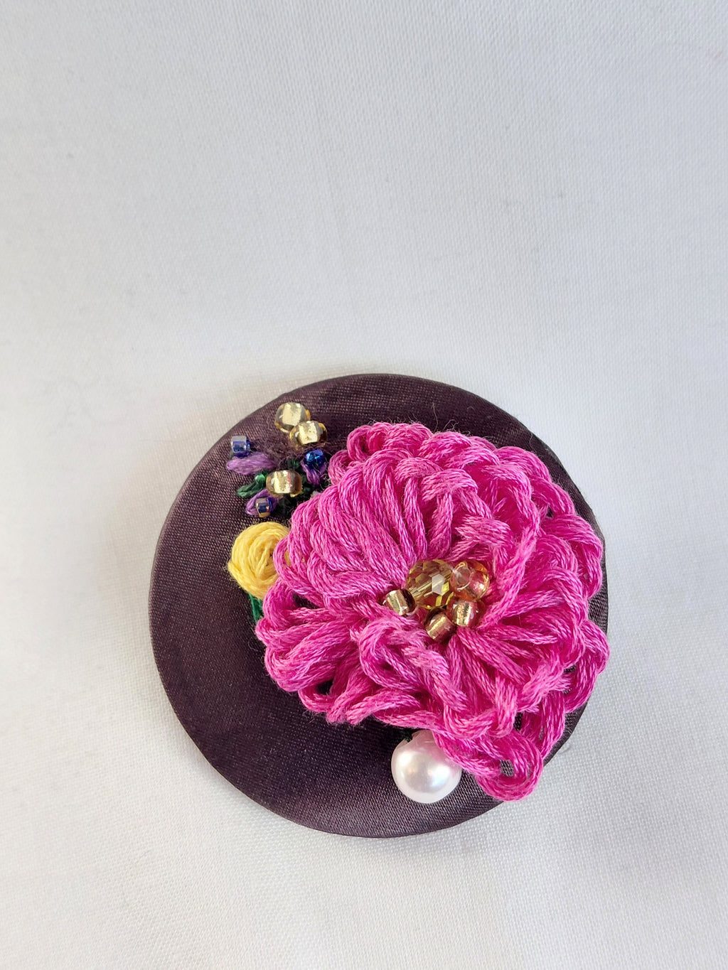 Decorative fuschia flower brooch on brown background