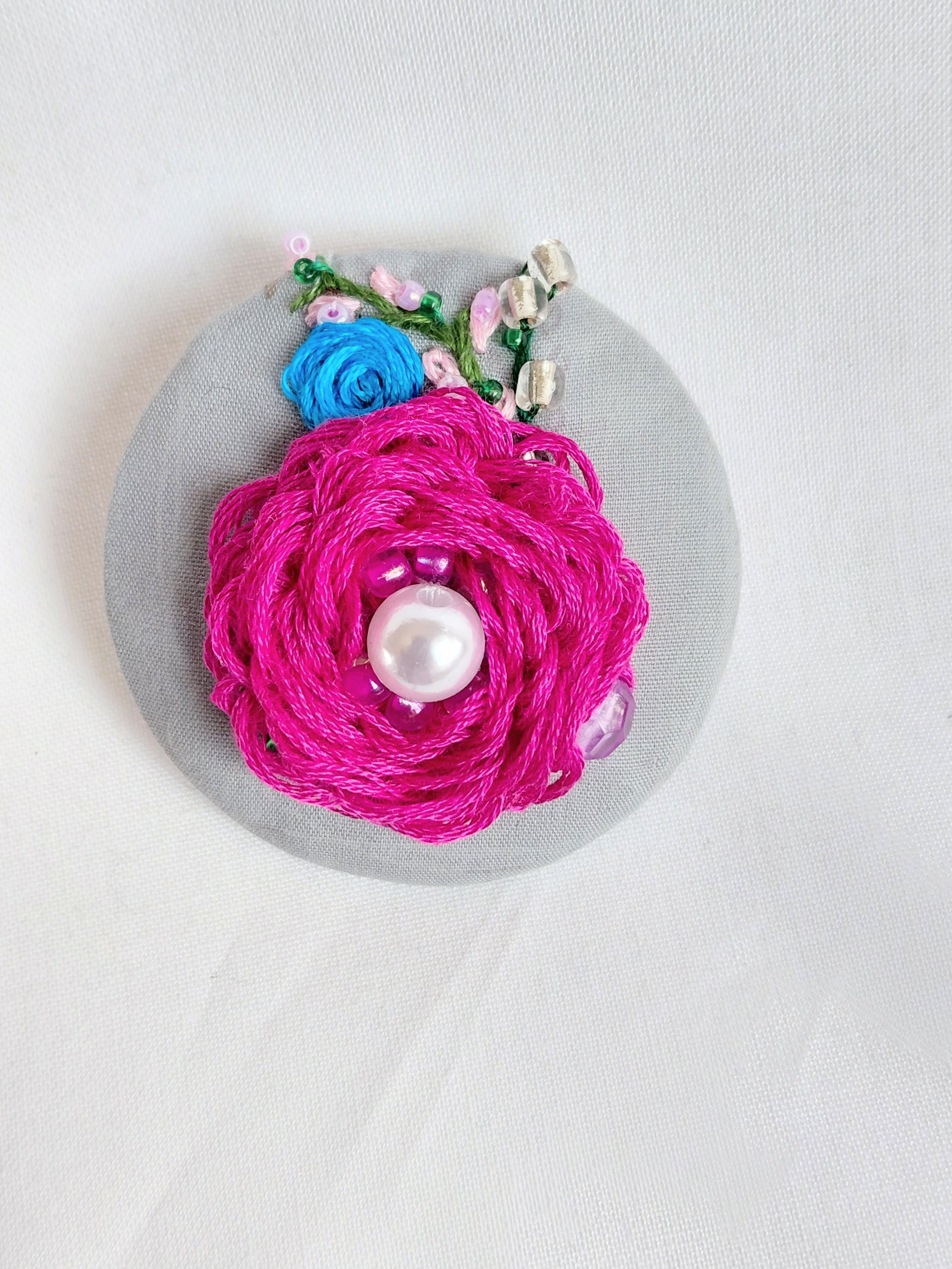 Decorative fuschia flower brooch on grey background
