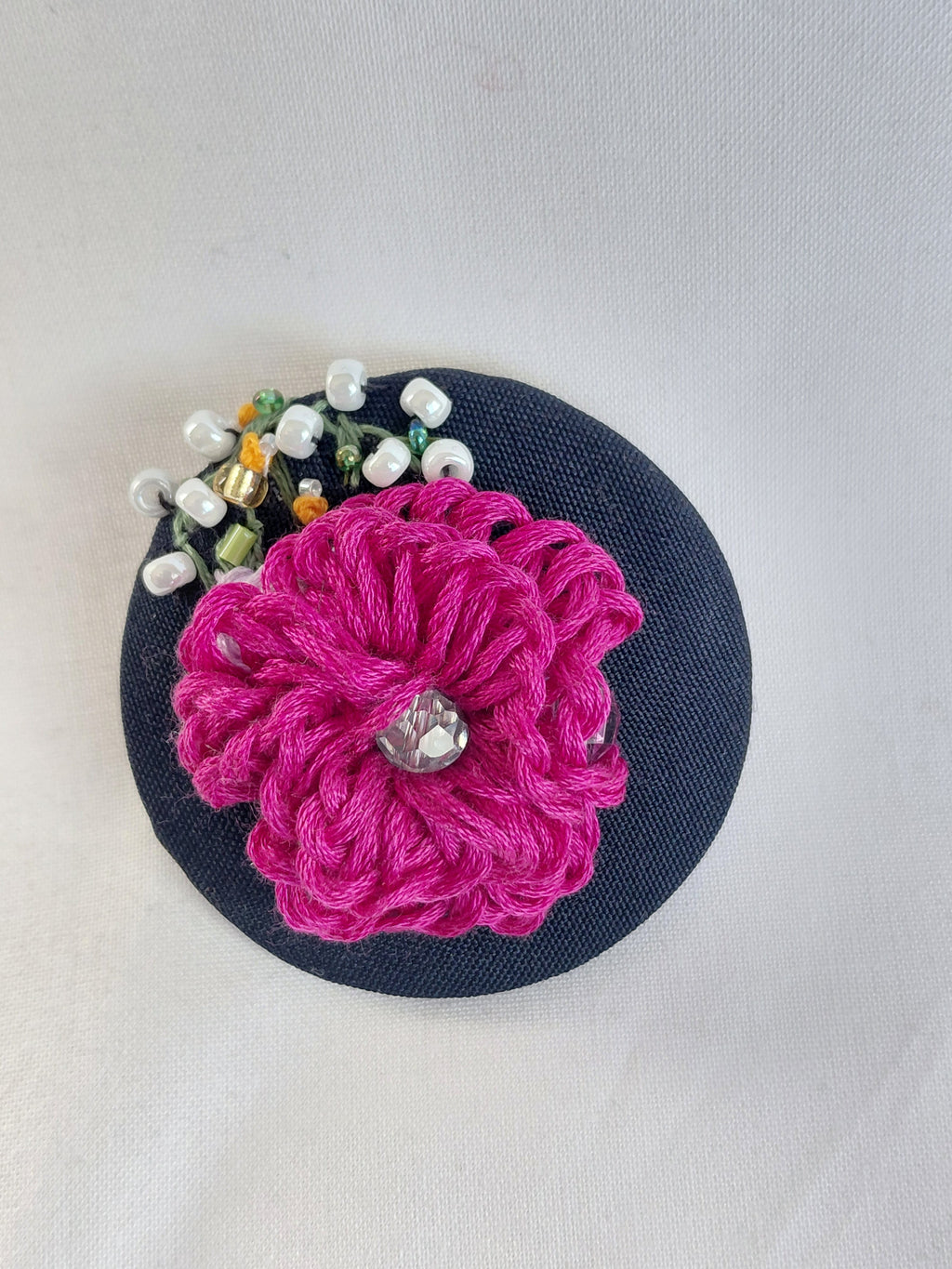 Decorative fuschia flower brooch on black background