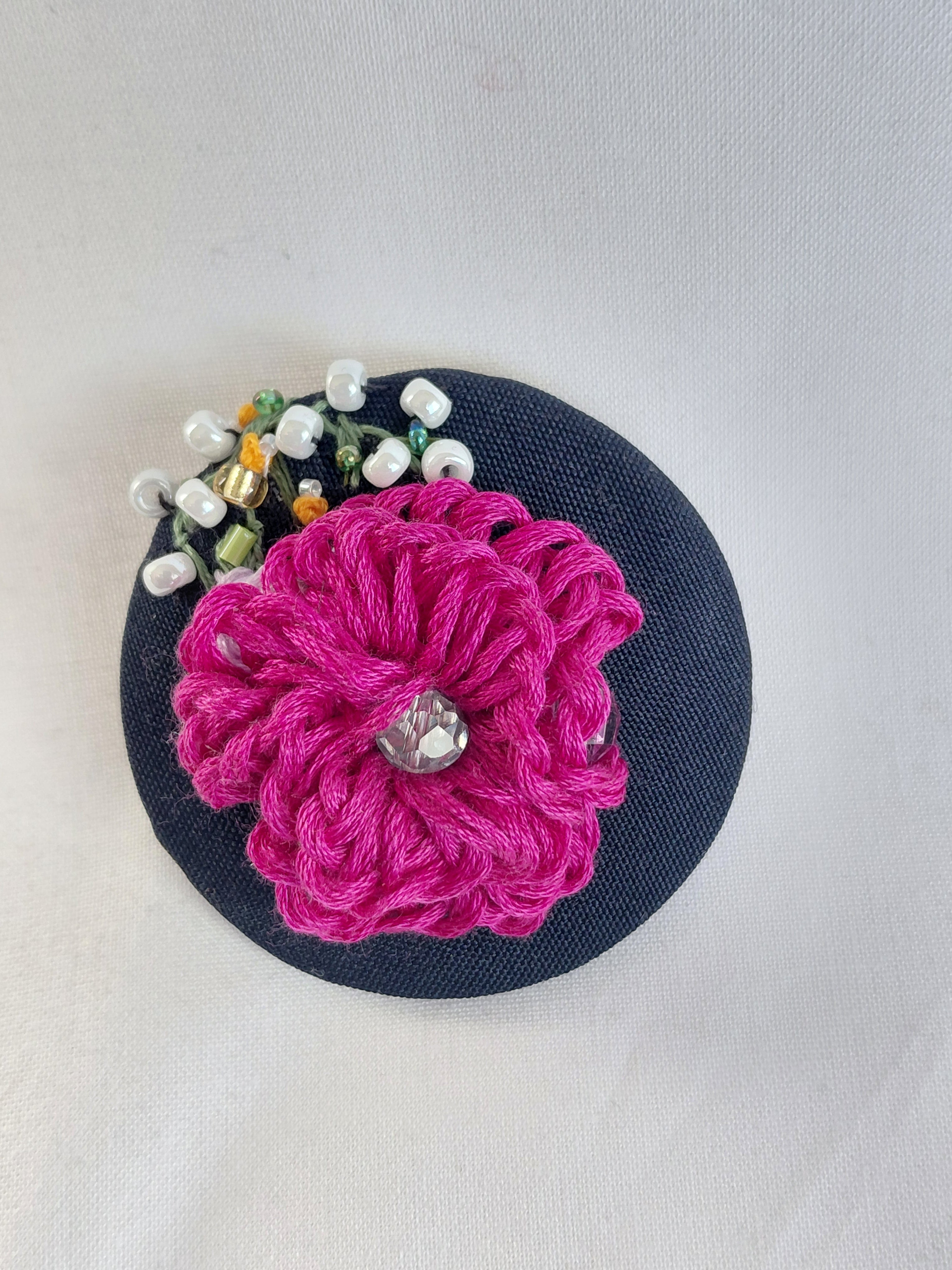 Decorative fuschia flower brooch on black background