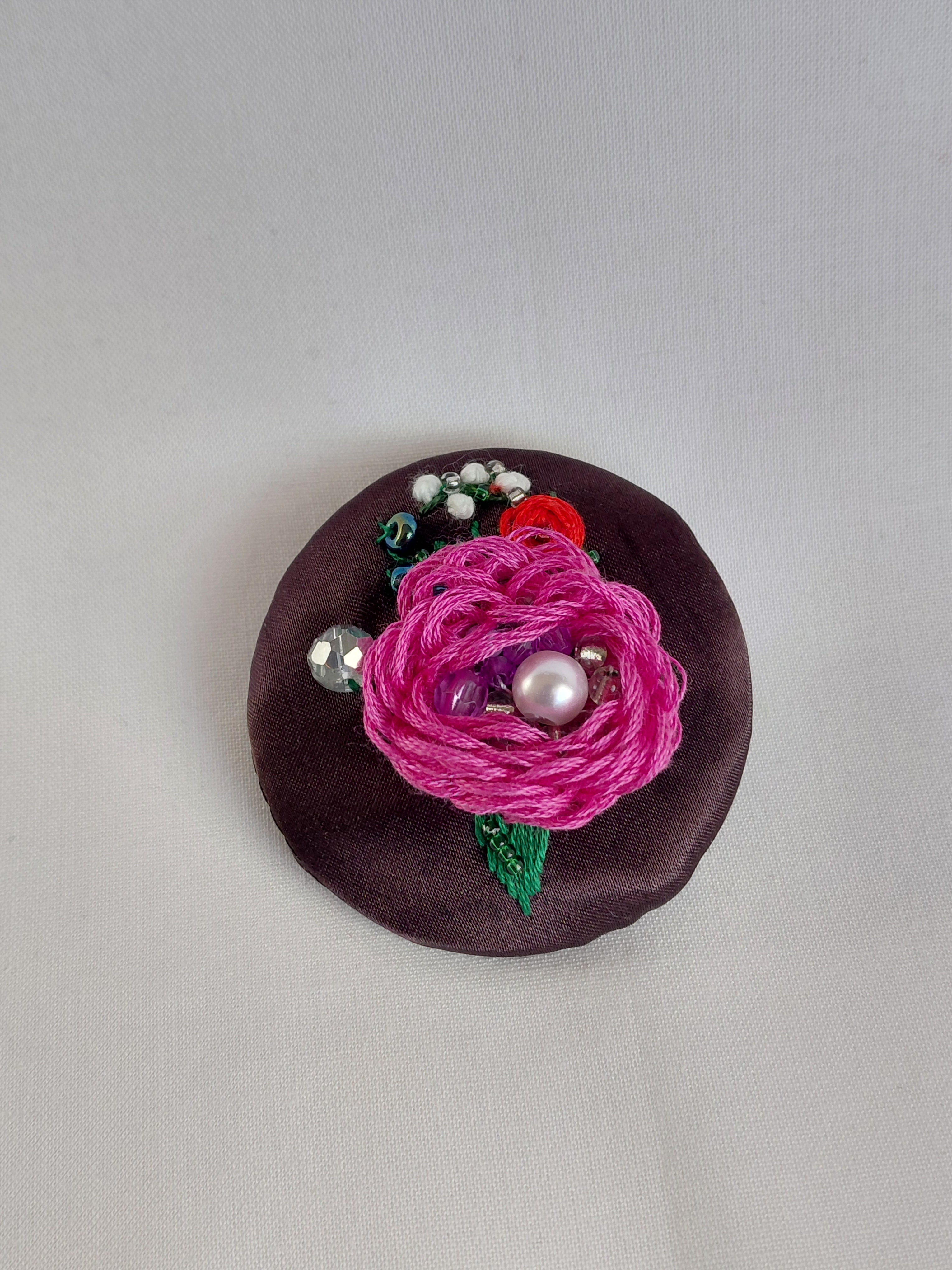 Decorative fuschia flower brooch on brown background