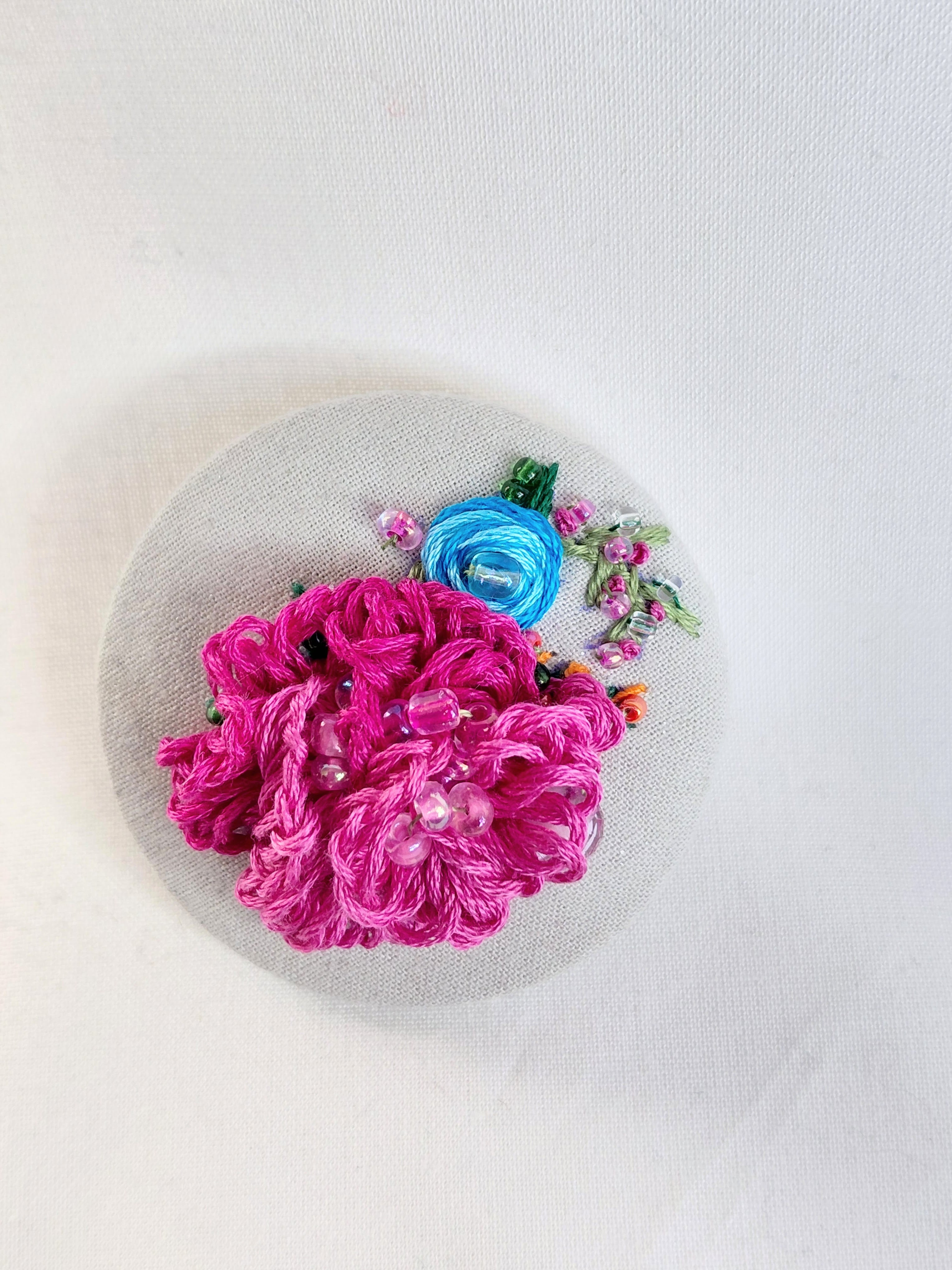 Decorative fuschia flower brooch on grey spec background