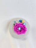 Decorative fuschia flower brooch on grey spec background