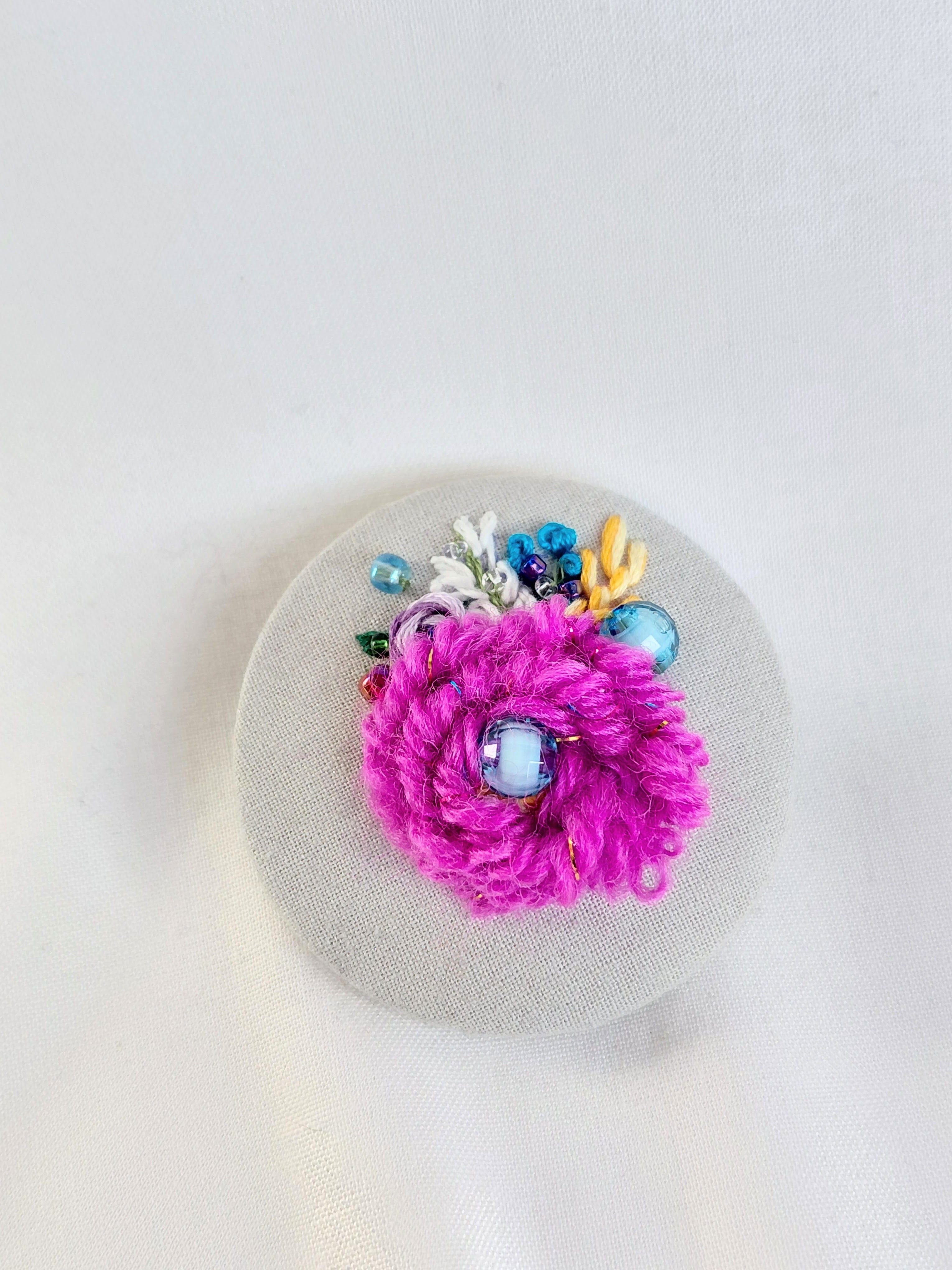 Decorative fuschia flower brooch on grey spec background