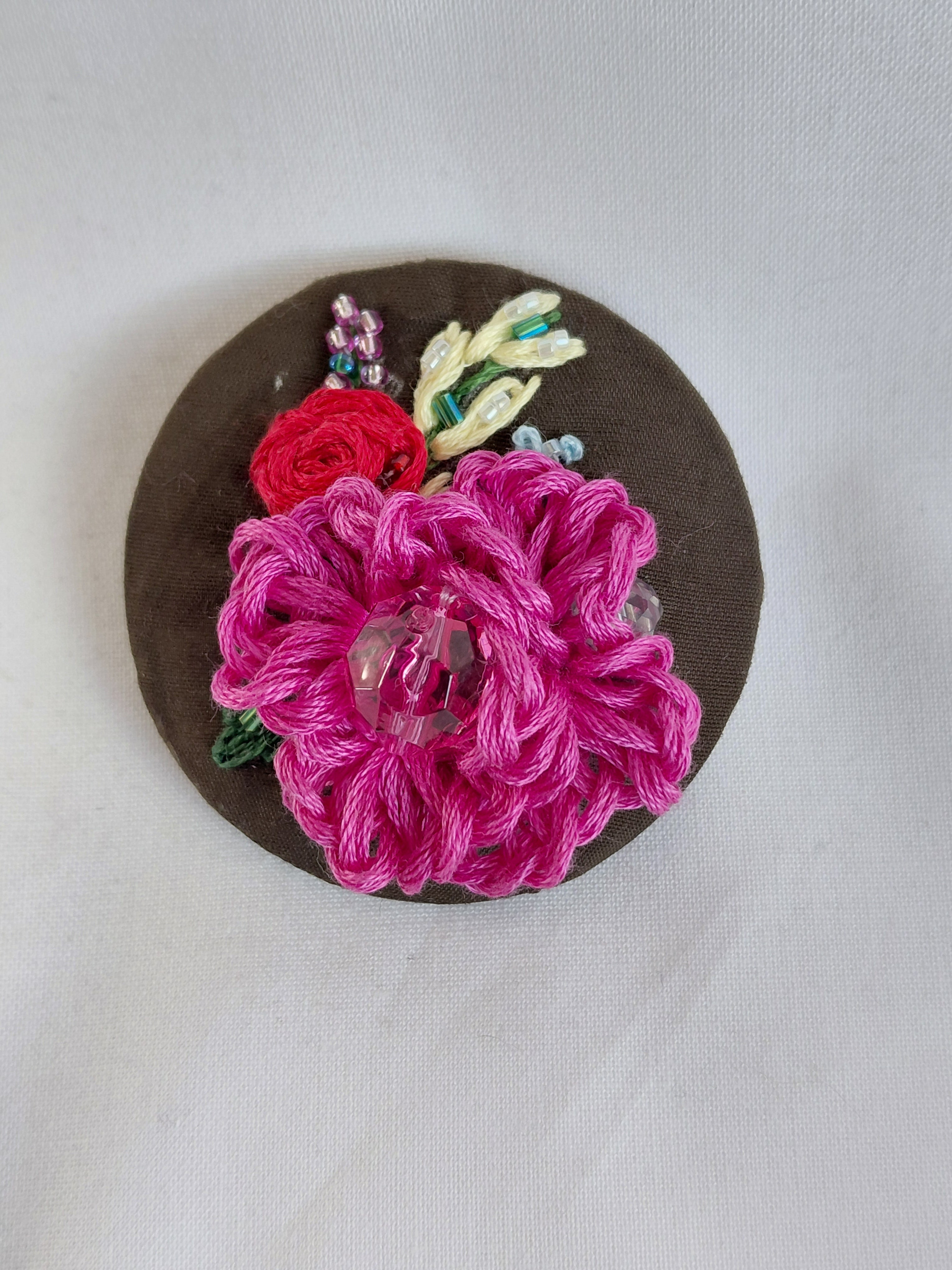 Decorative fuschia flower brooch on olive background