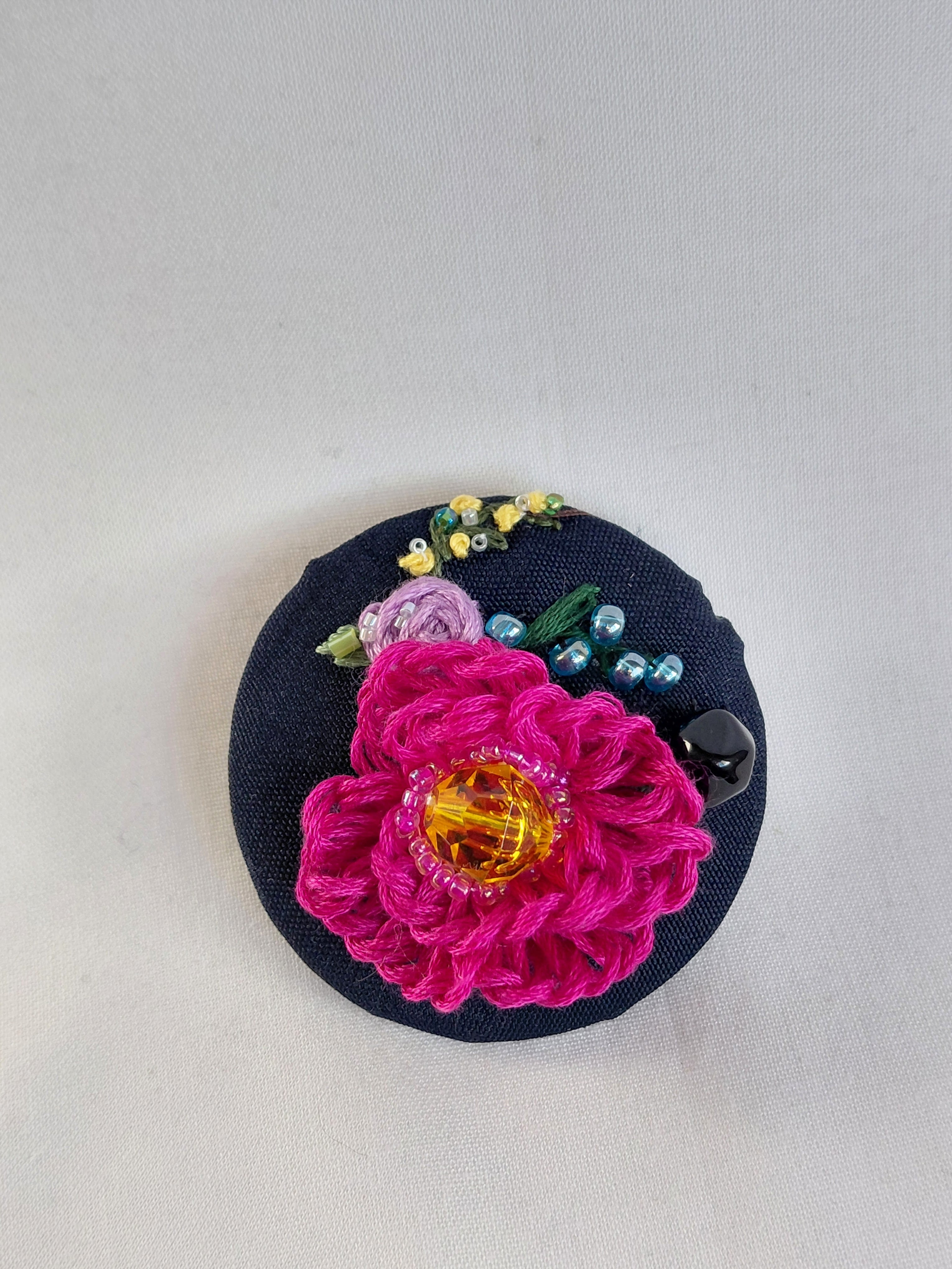 Decorative fuschia flower brooch on black background