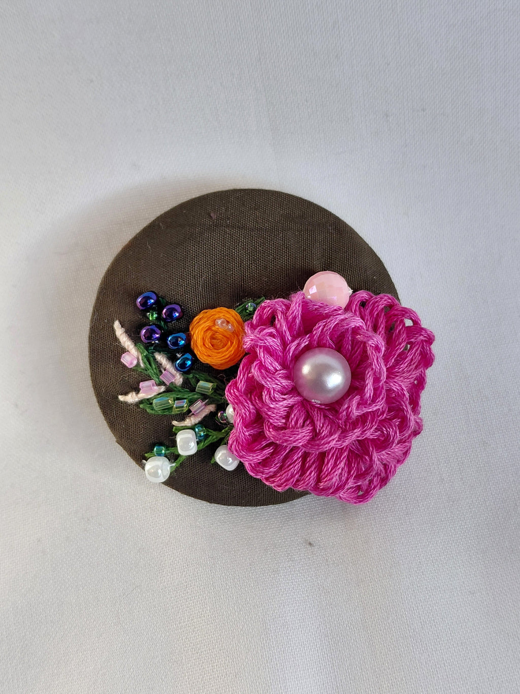 Decorative fuschia flower brooch on olive background