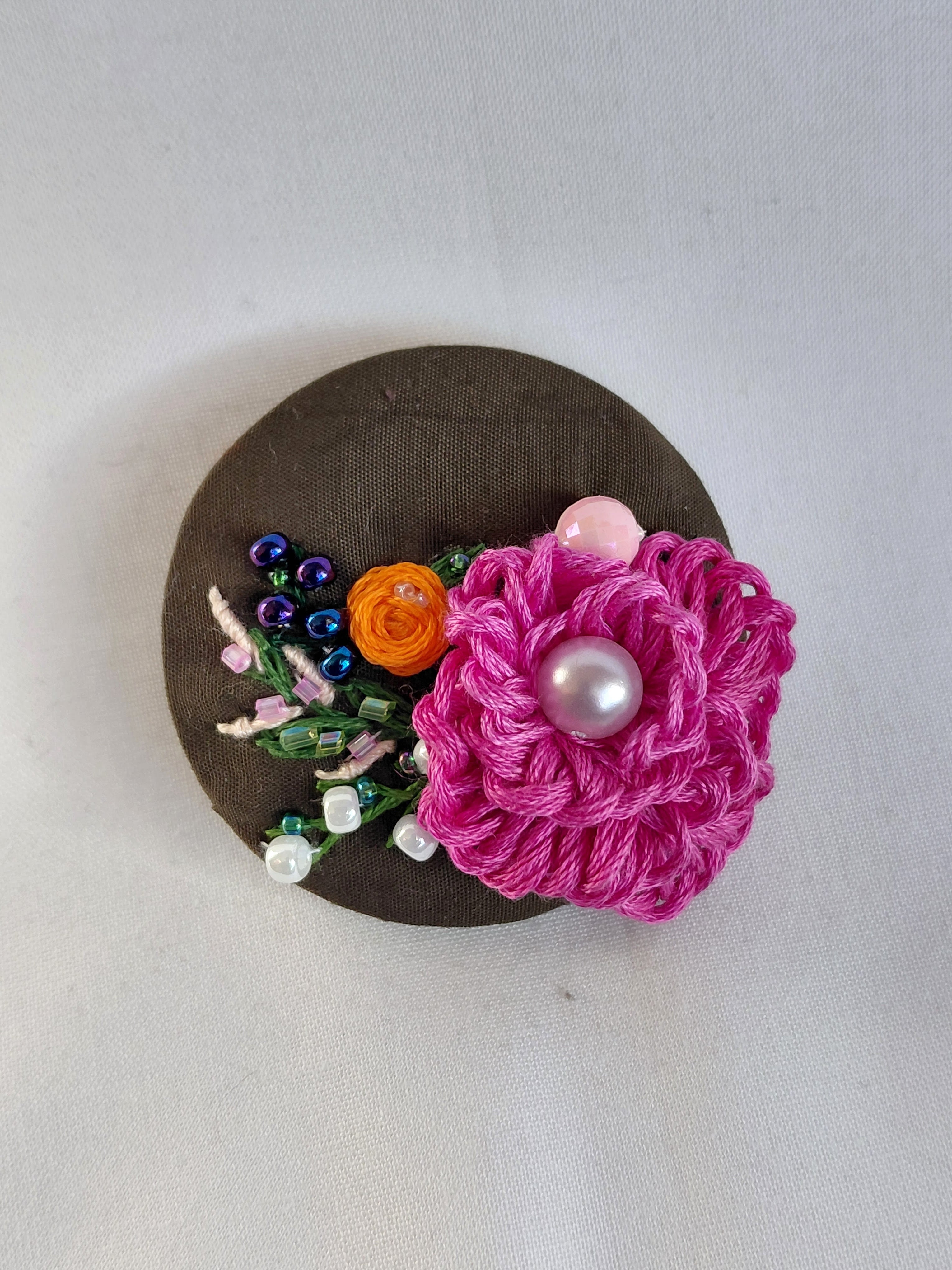 Decorative fuschia flower brooch on olive background