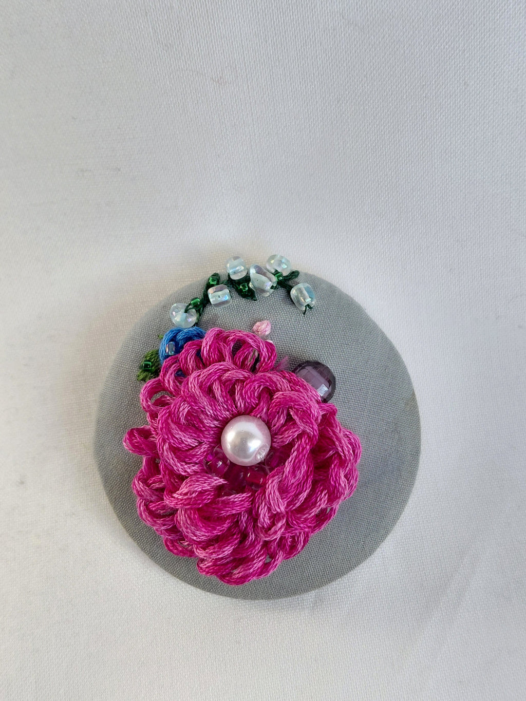 Decorative fuschia flower brooch on grey background