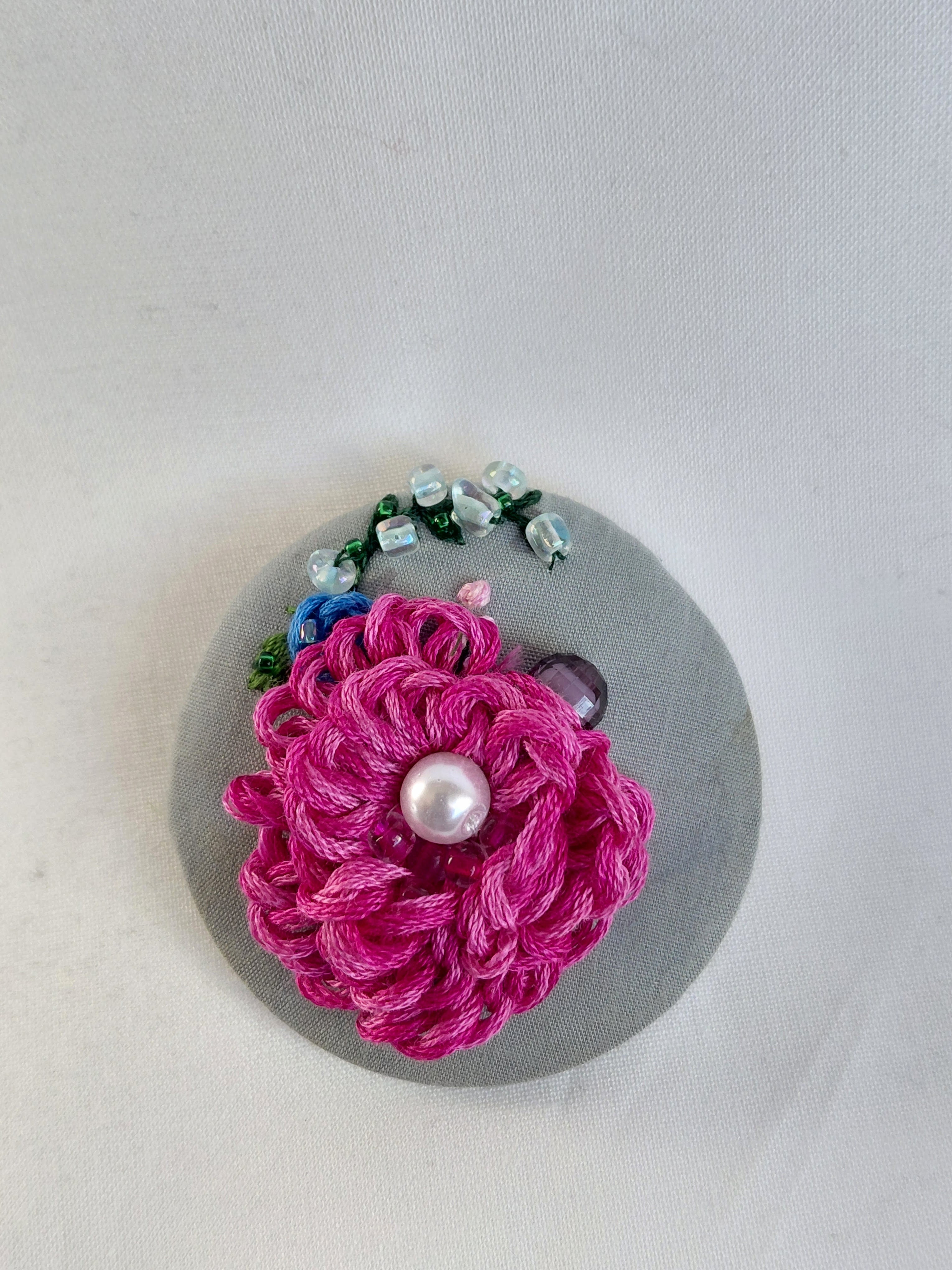 Decorative fuschia flower brooch on grey background