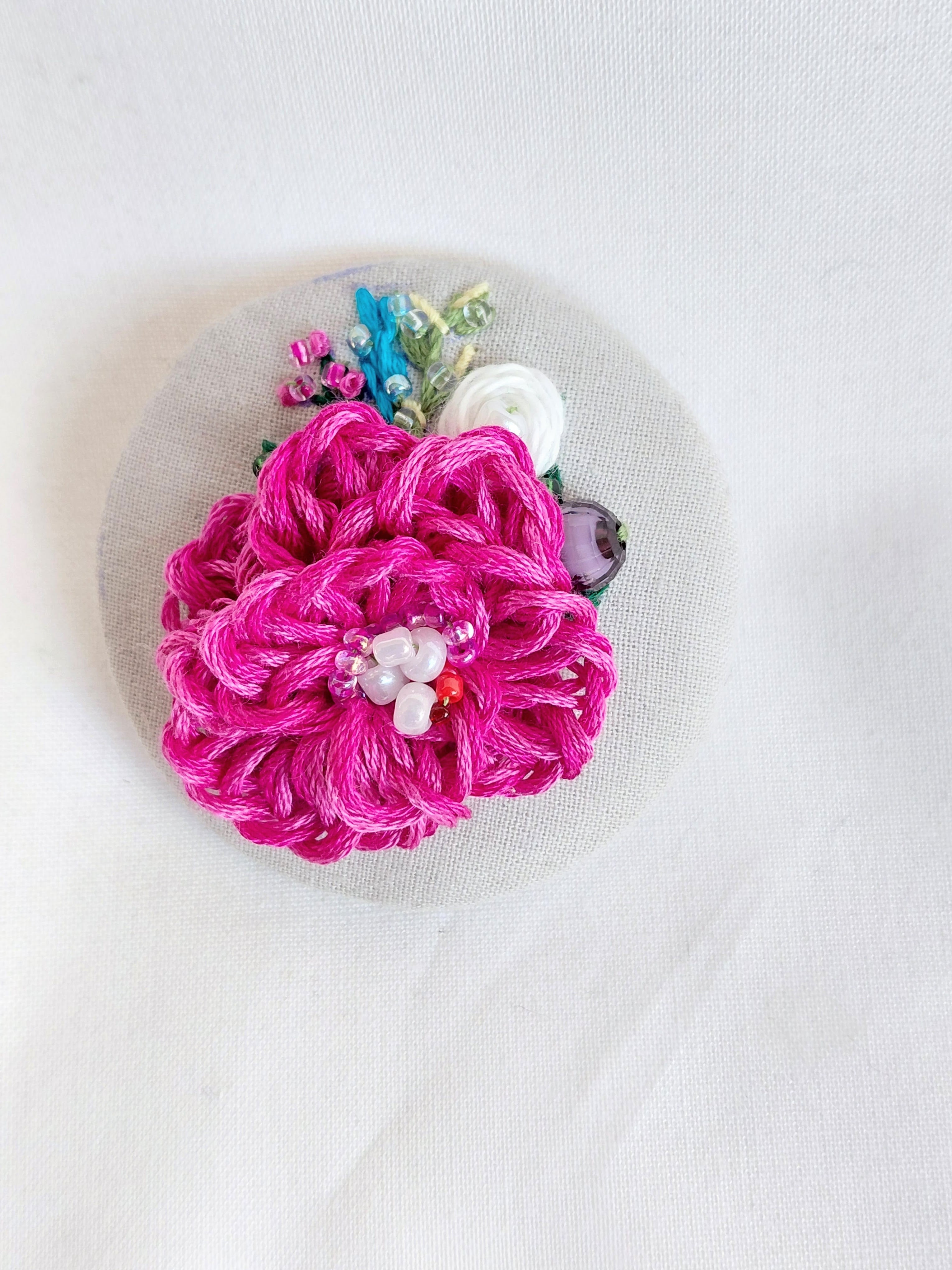 Decorative fuschia flower brooch on grey spec background