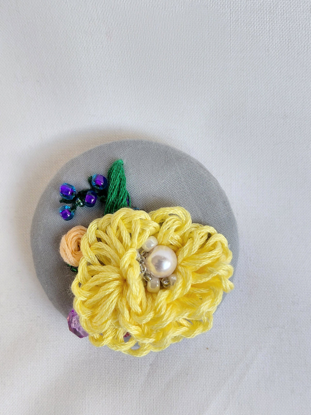 Decorative yellow flower brooch on grey background