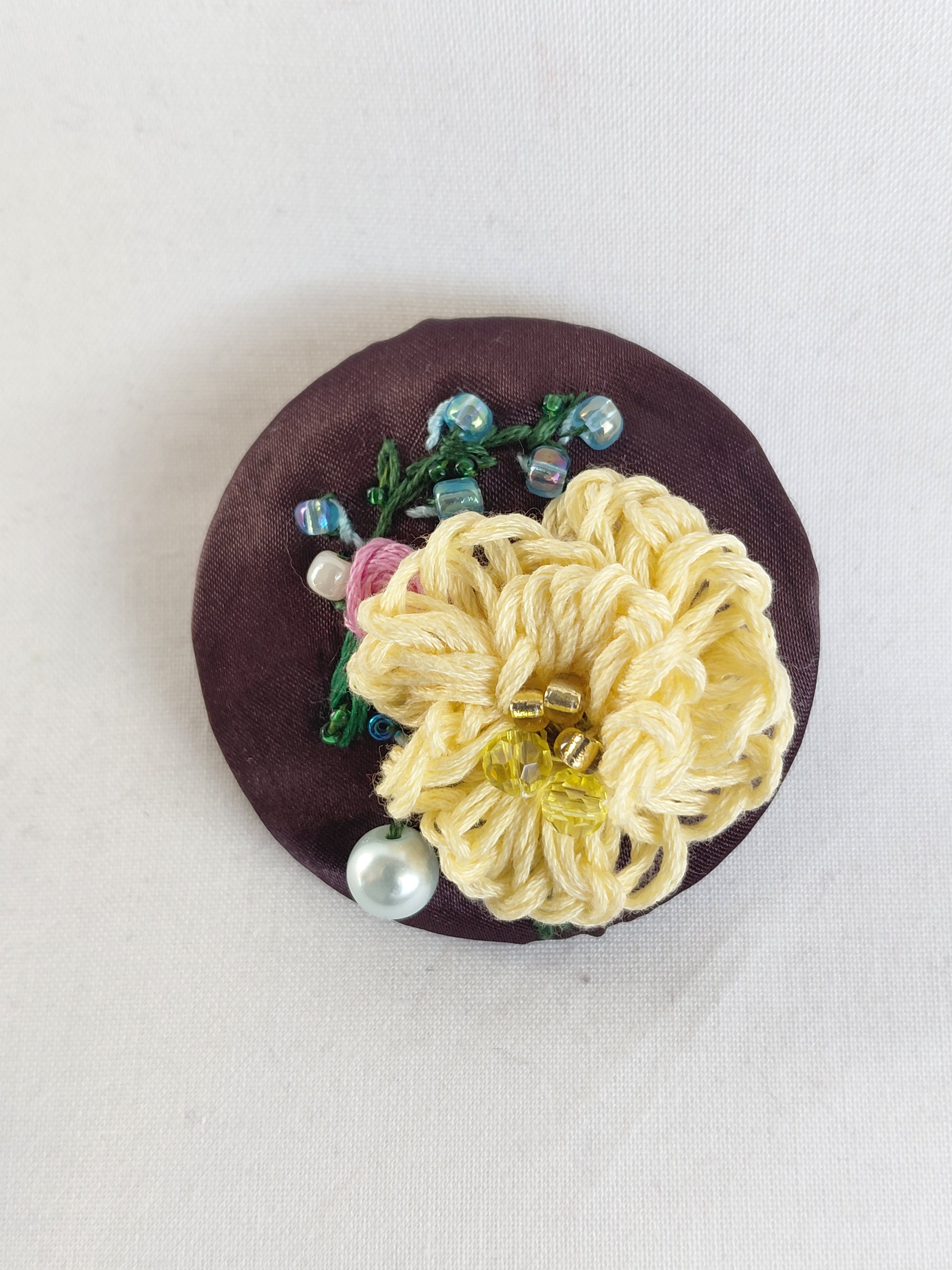 Decorative yellow flower brooch on brown background