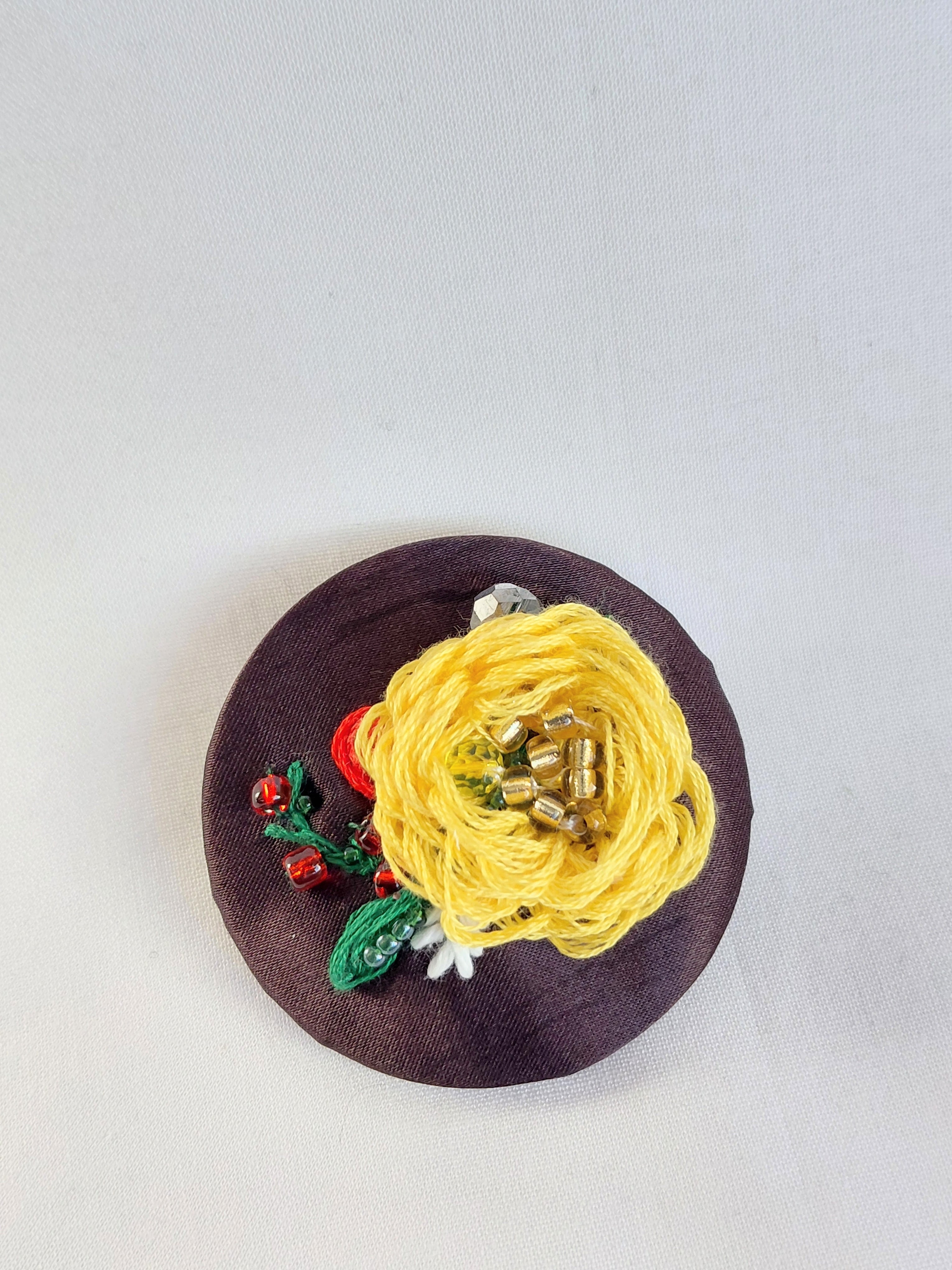 Decorative yellow flower brooch on brown background