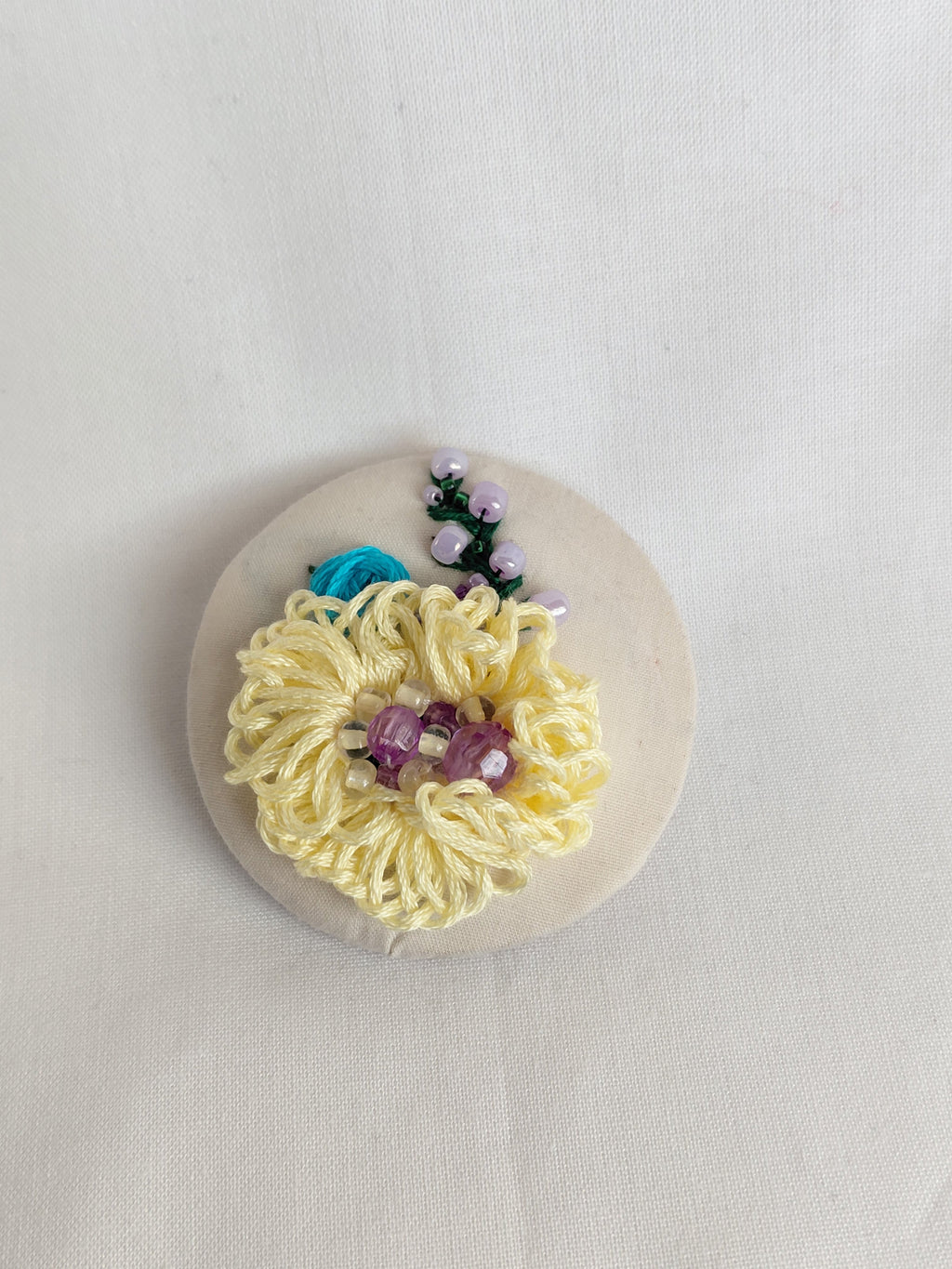 Decorative yellow flower brooch on cream background