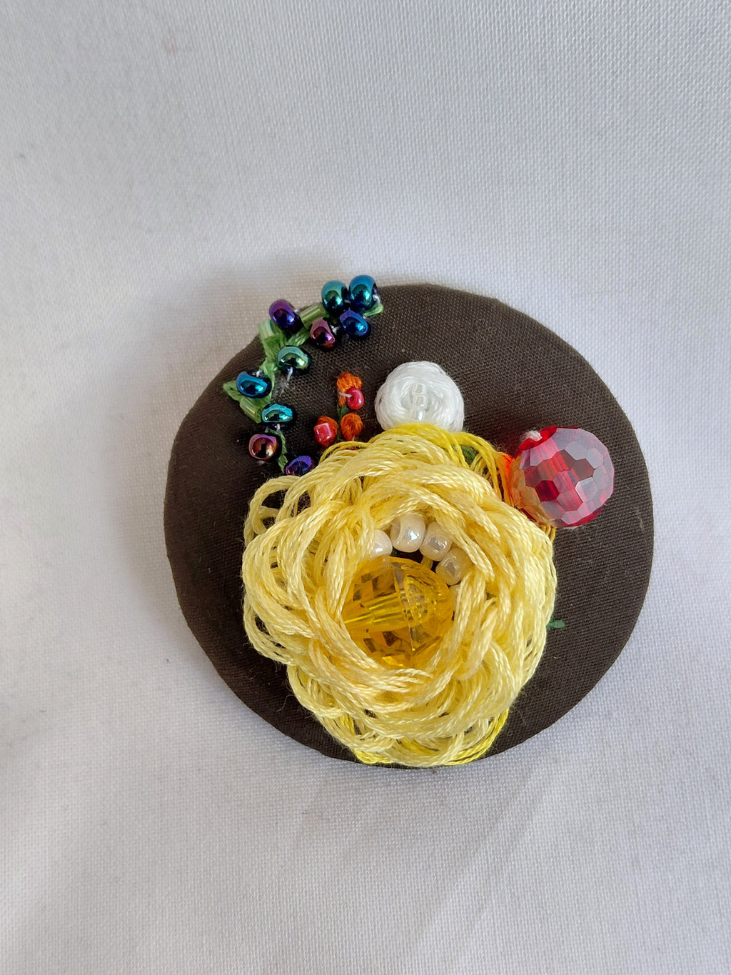 Decorative yellow flower brooch on olive background