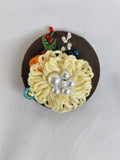 Decorative yellow flower brooch on olive background