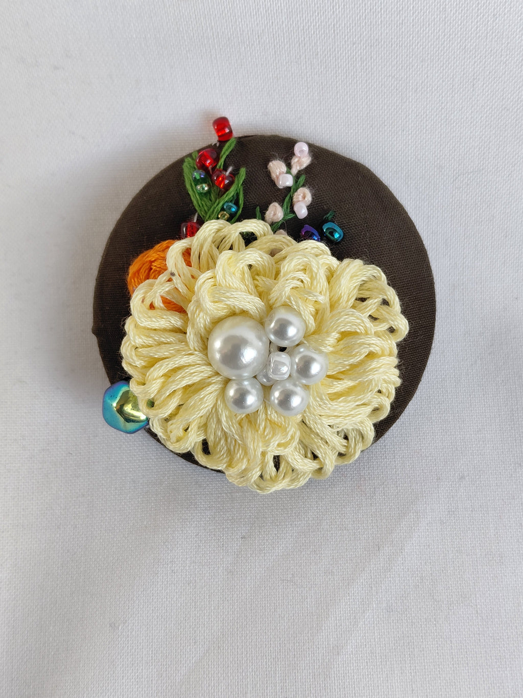 Decorative yellow flower brooch on olive background