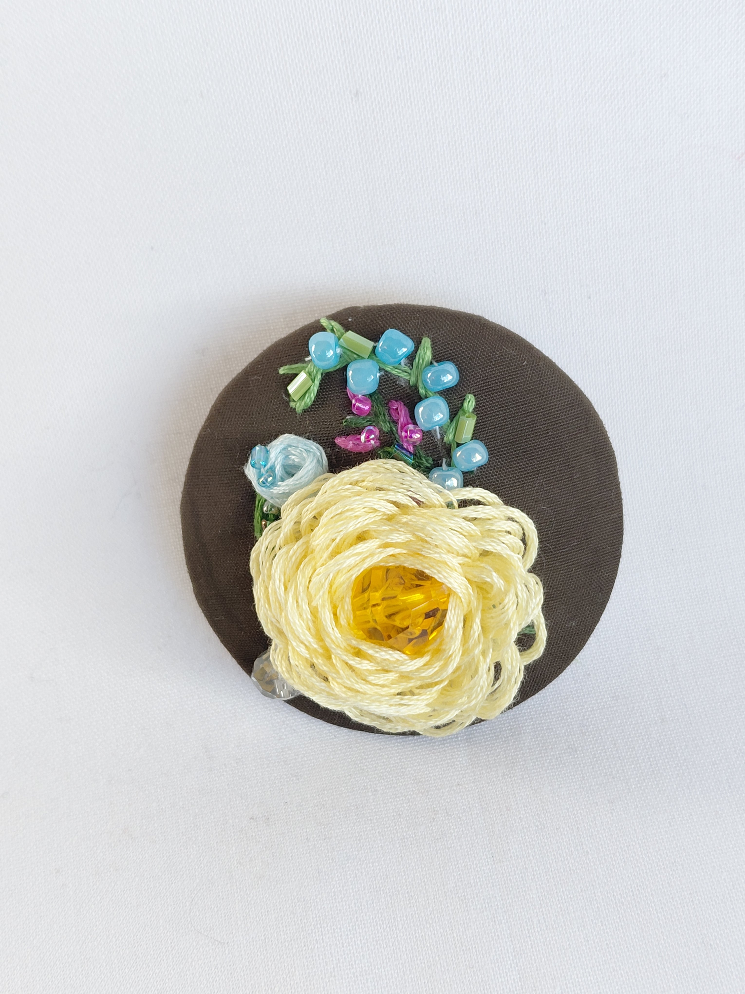 Decorative yellow flower brooch on olive background