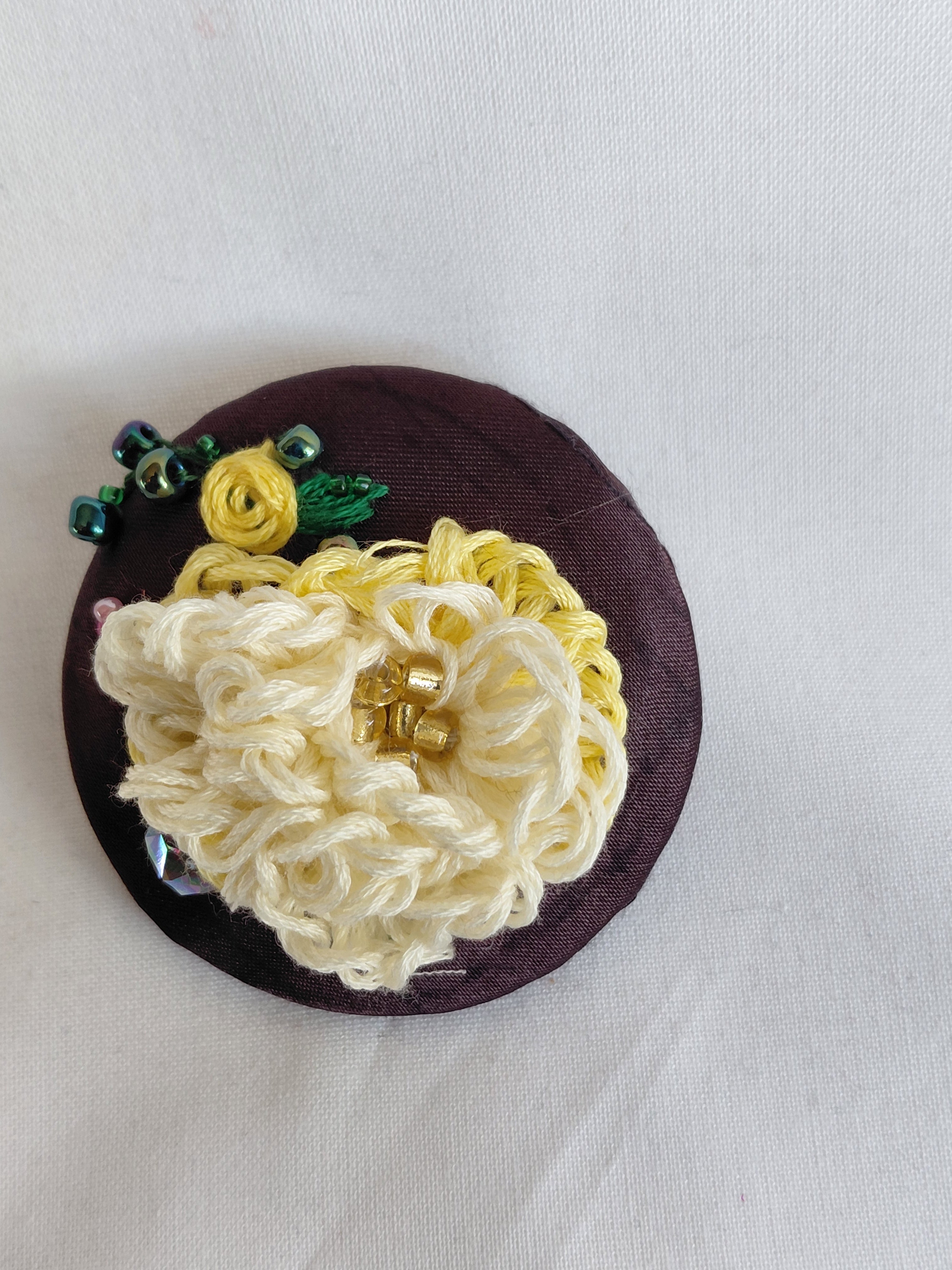 Decorative yellow flower brooch on brown background