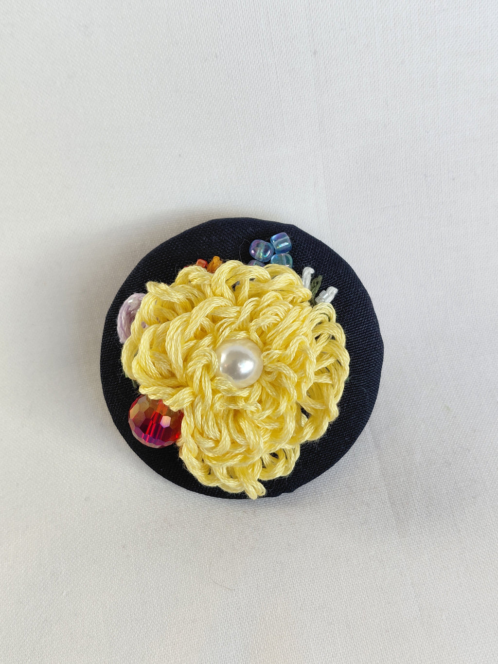 Decorative yellow flower brooch on black background