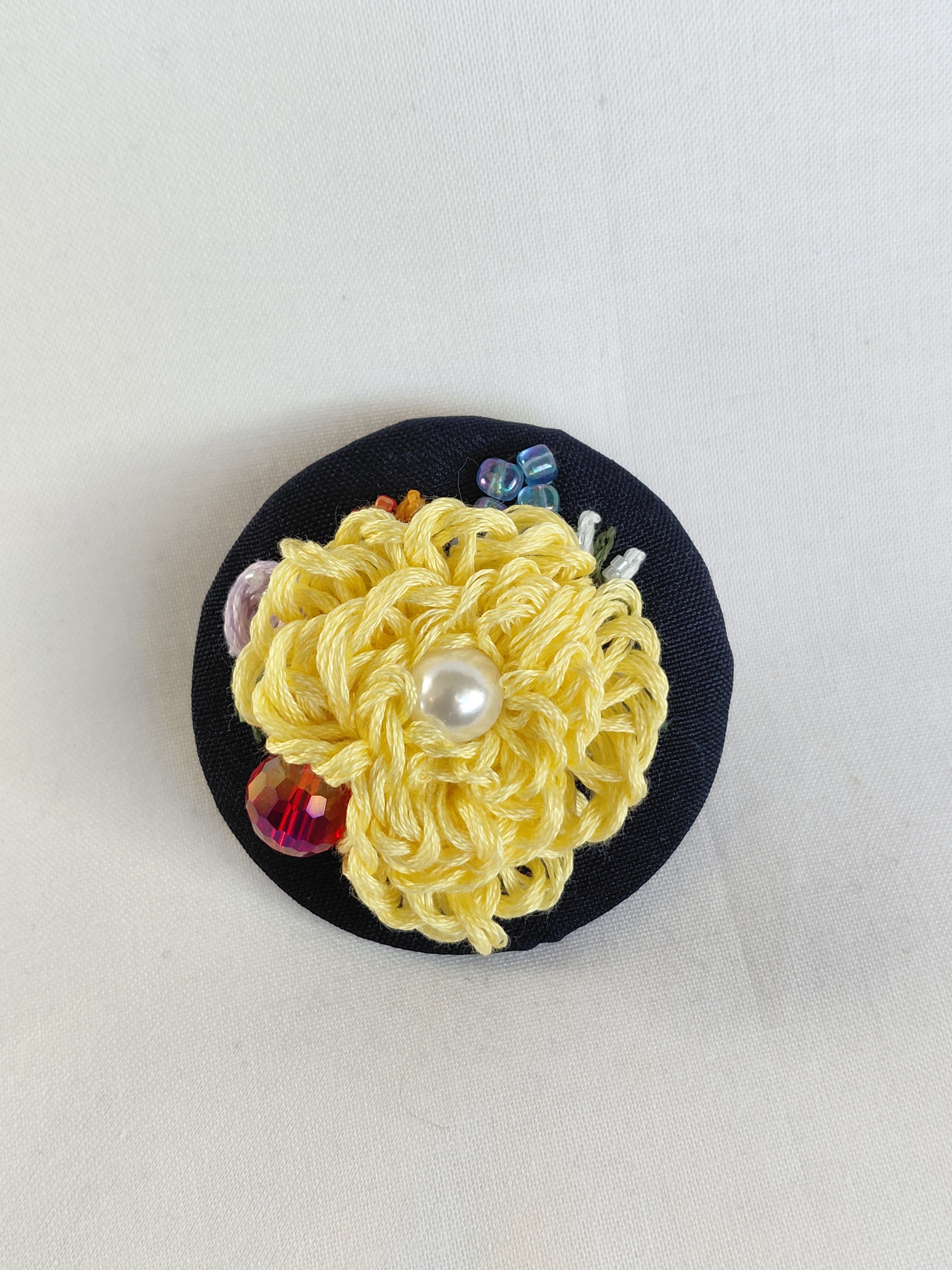 Decorative yellow flower brooch on black background