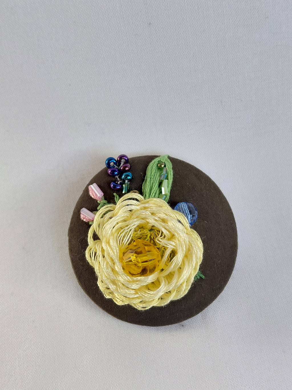 Decorative yellow flower brooch on olive background
