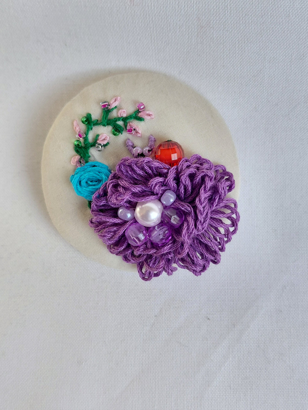 Decorative purple flower brooch on cream background