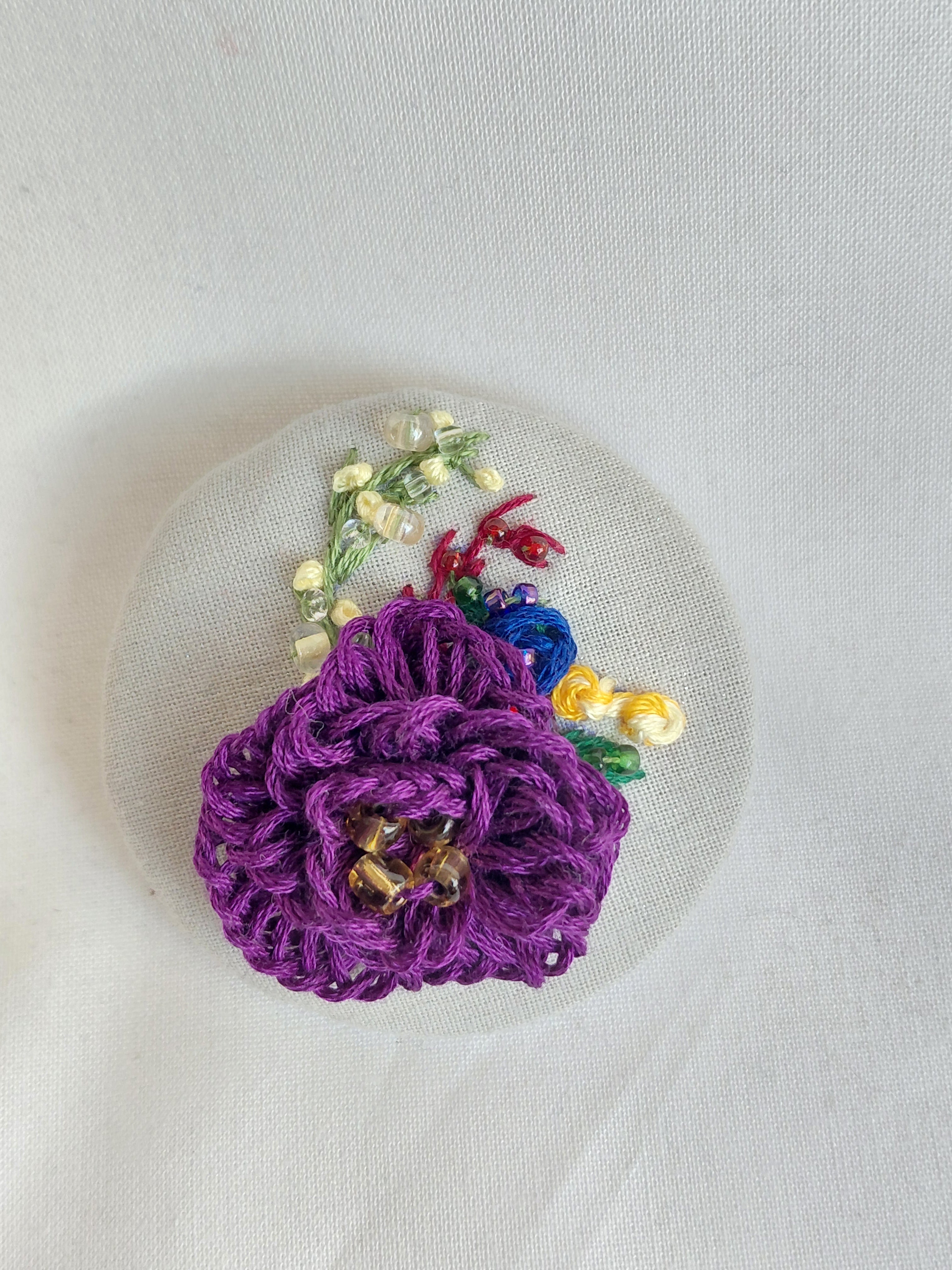Decorative purple flower brooch on grey spec background