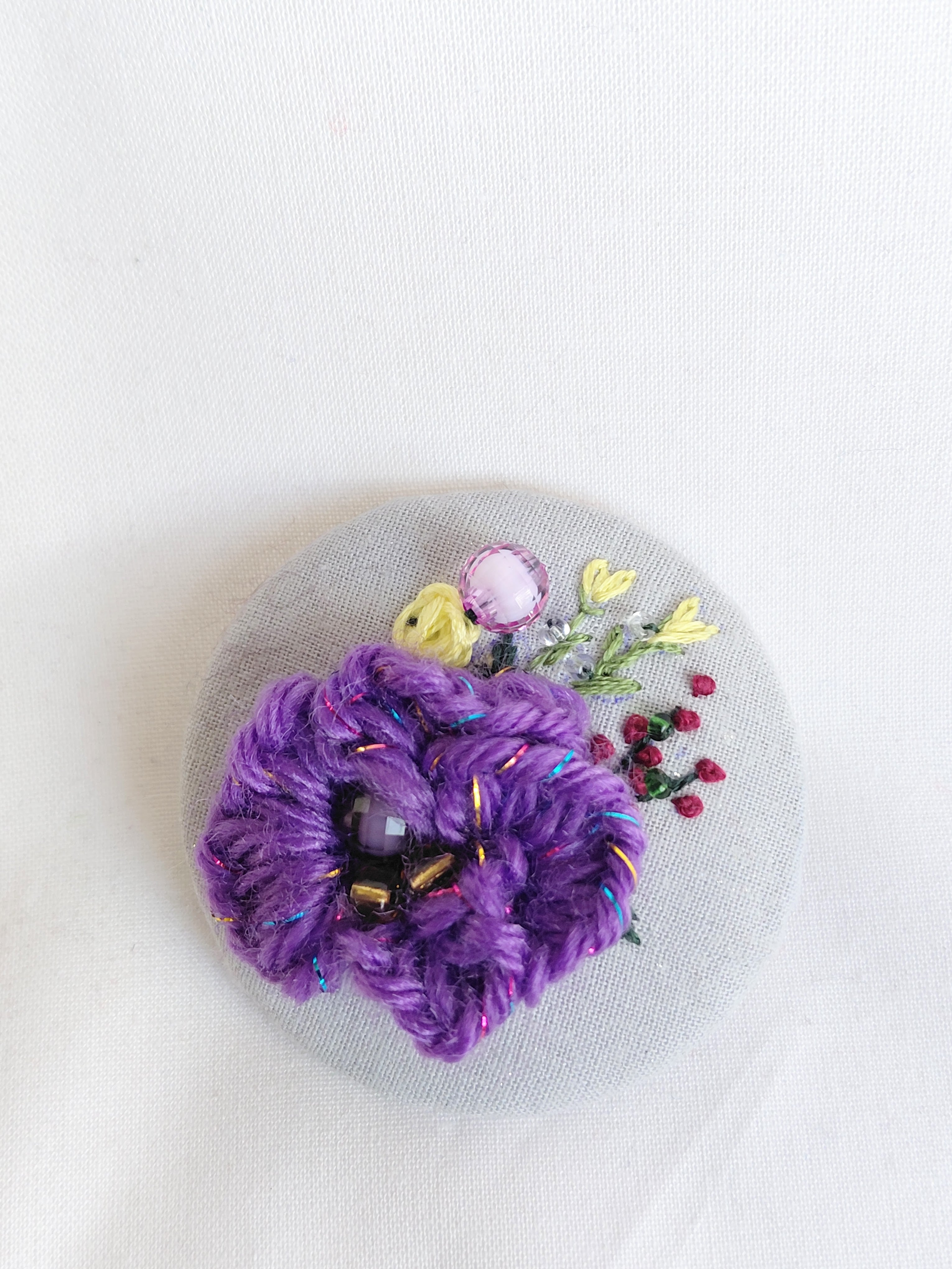 Decorative purple flower brooch on blue spec background