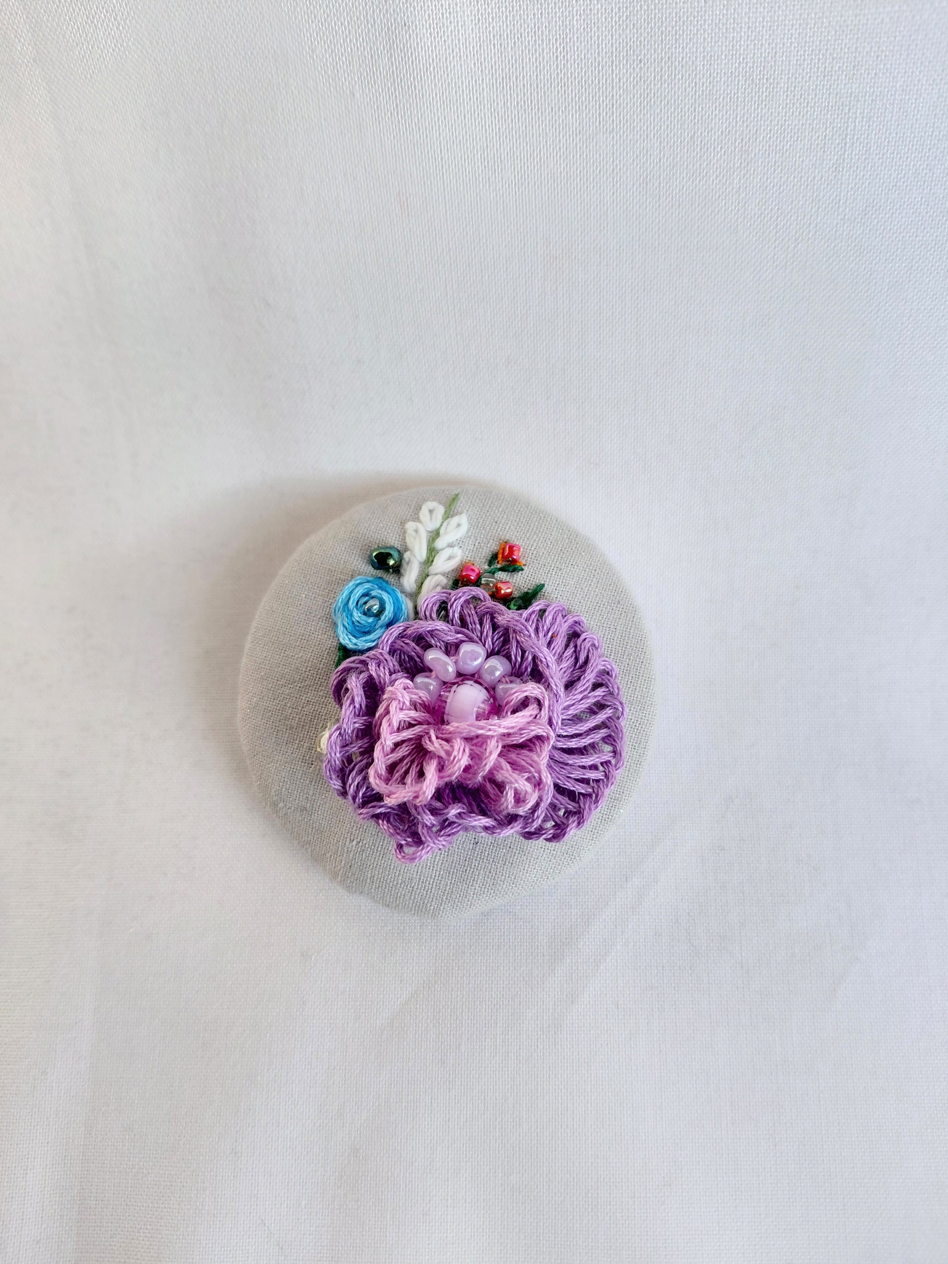 Decorative purple flower brooch on grey spec background