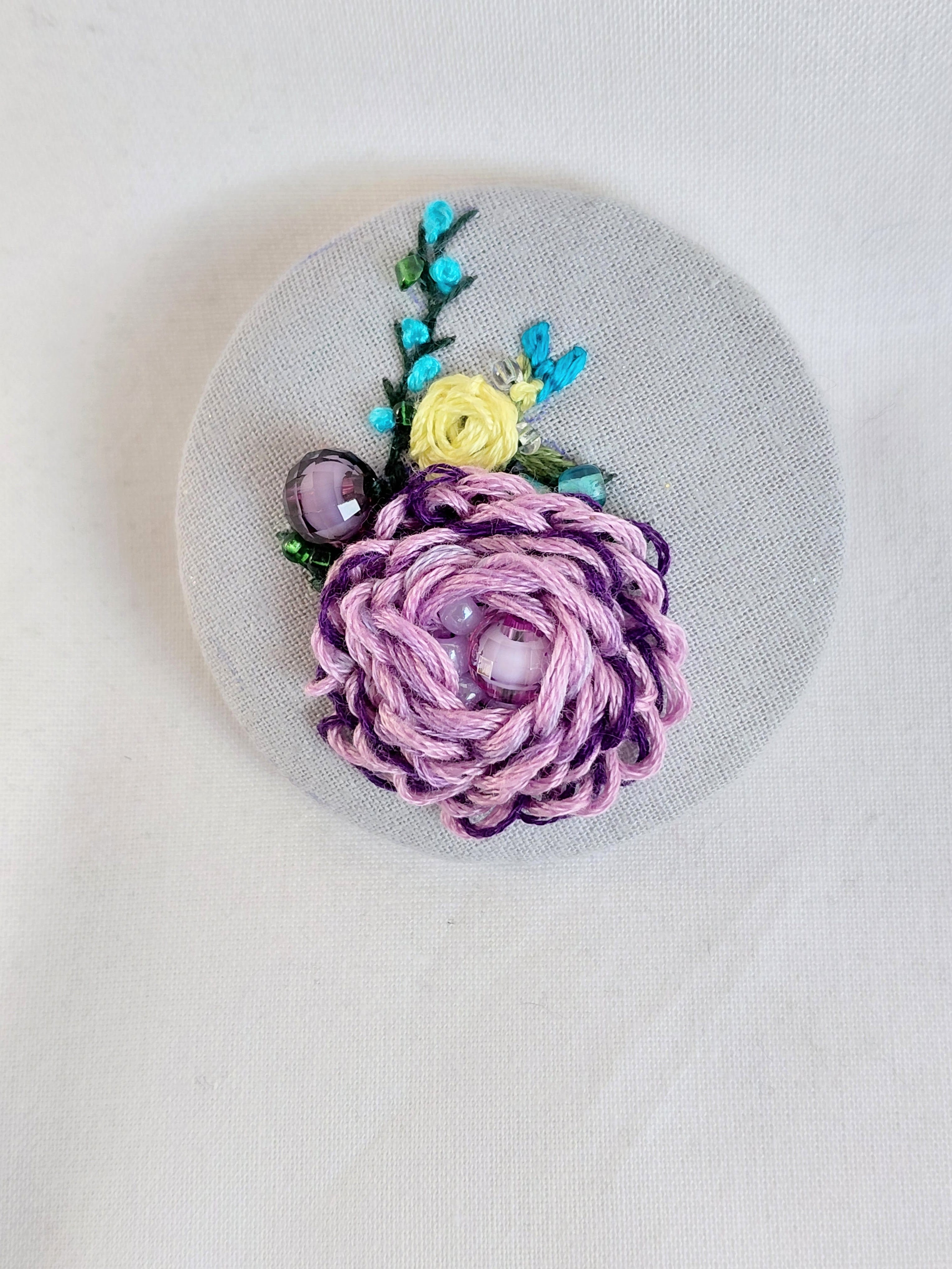 Decorative purple flower brooch on blue spec background
