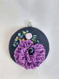 Decorative purple flower brooch on black background