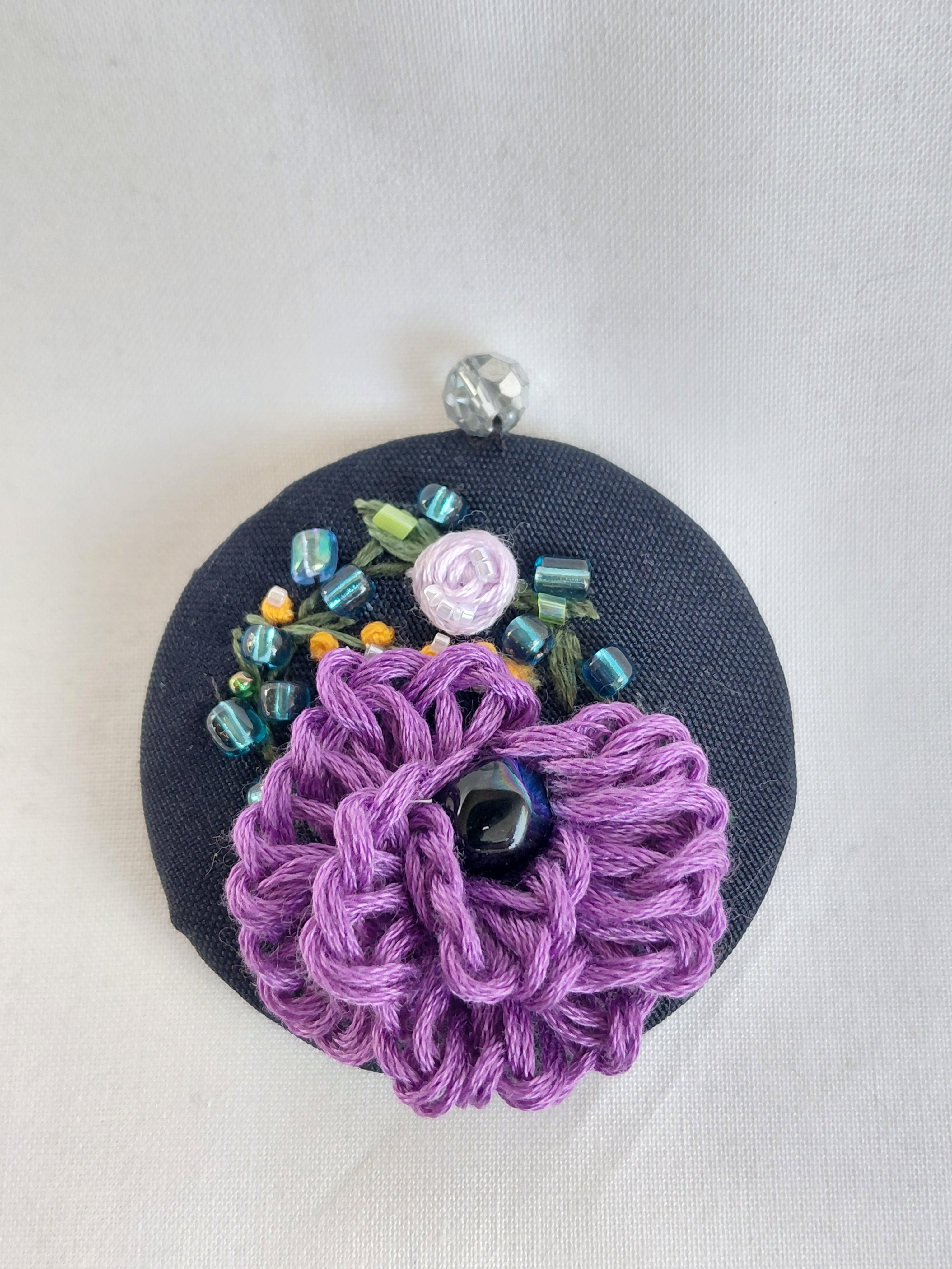 Decorative purple flower brooch on black background