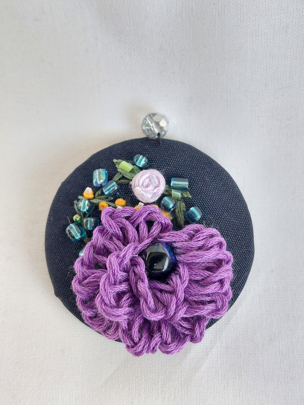 Decorative purple flower brooch on black background