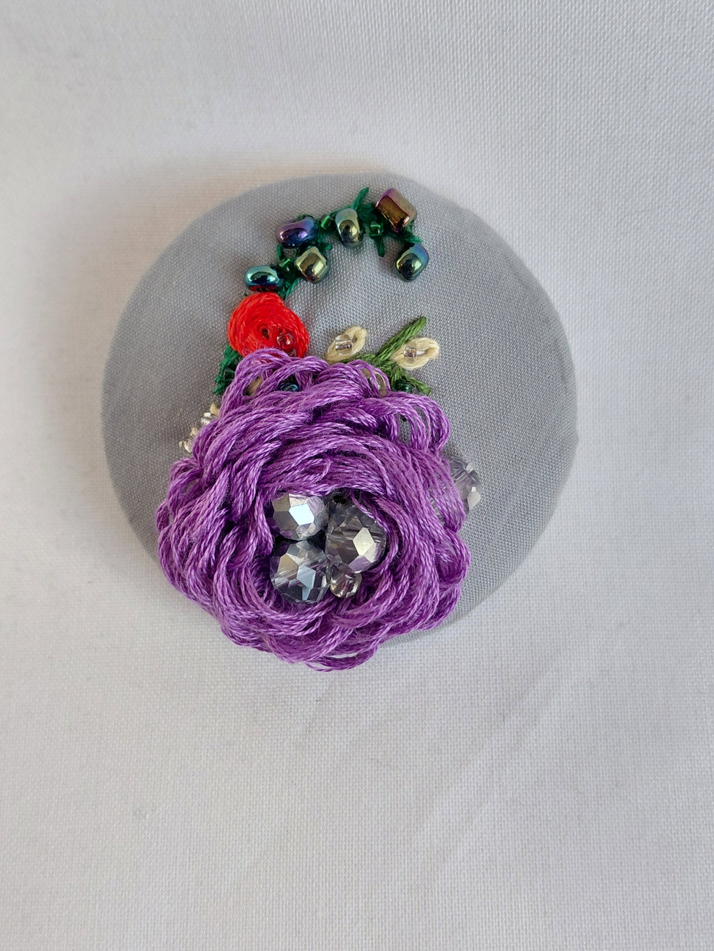 Decorative purple flower brooch on grey background