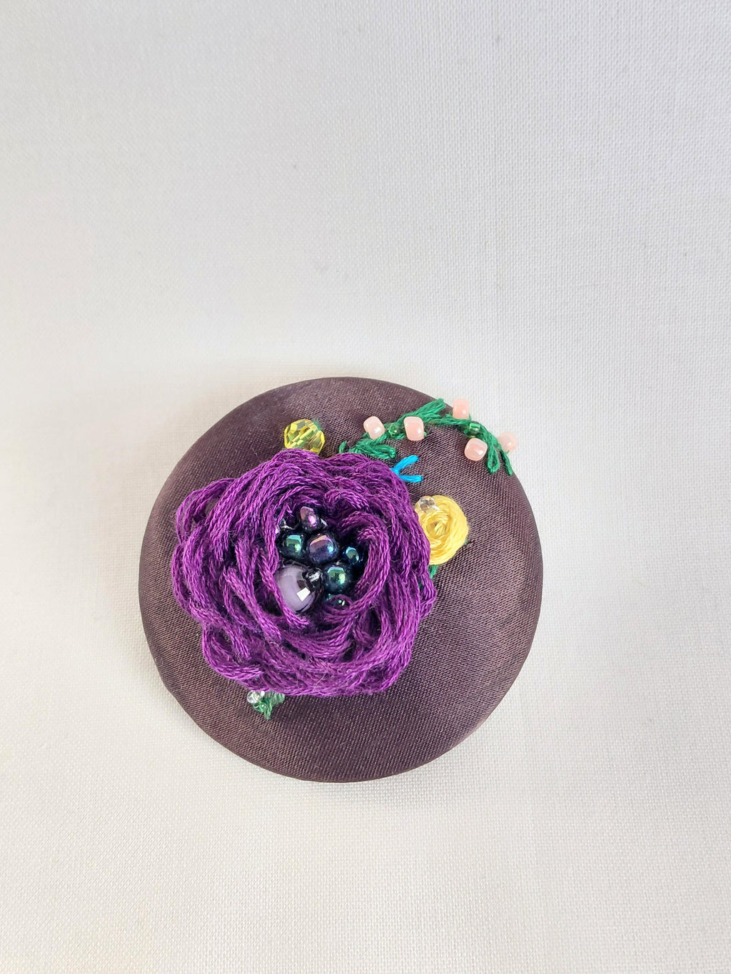 Decorative purple flower brooch on brown background