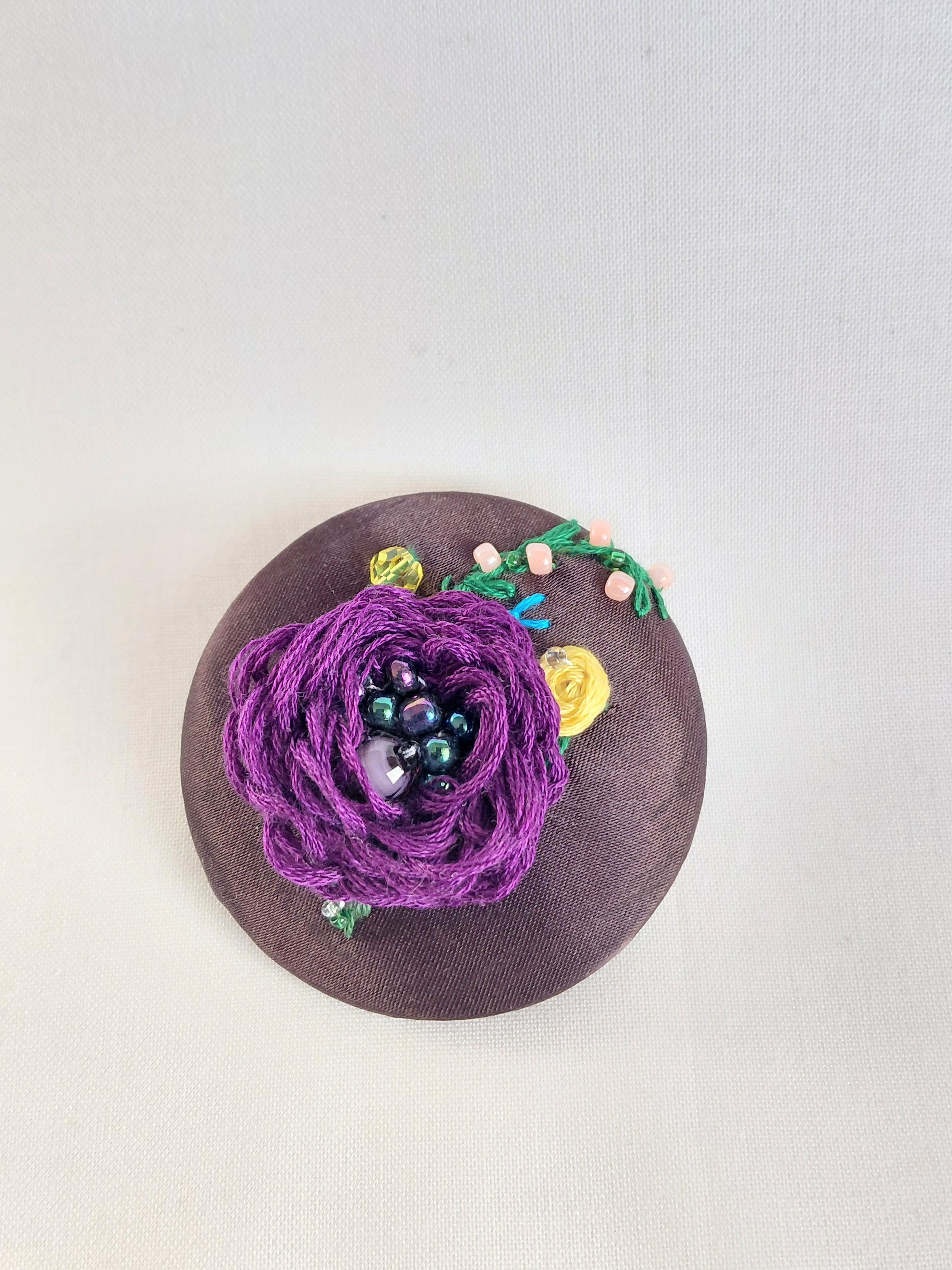 Decorative purple flower brooch on brown background