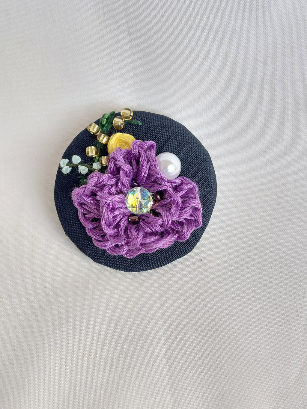 Decorative purple flower brooch on black background