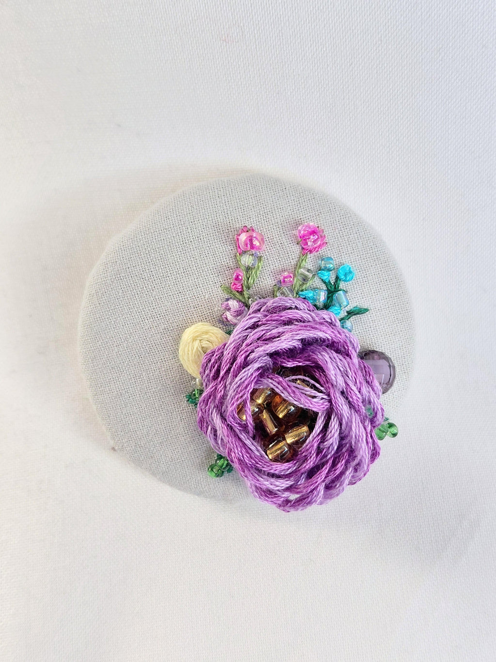 Decorative purple flower brooch on grey spec background