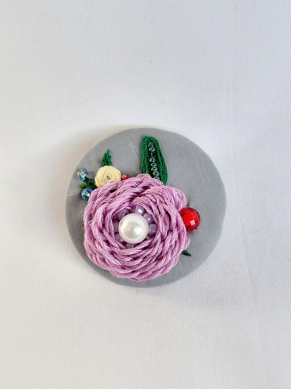Decorative purple flower brooch on grey background