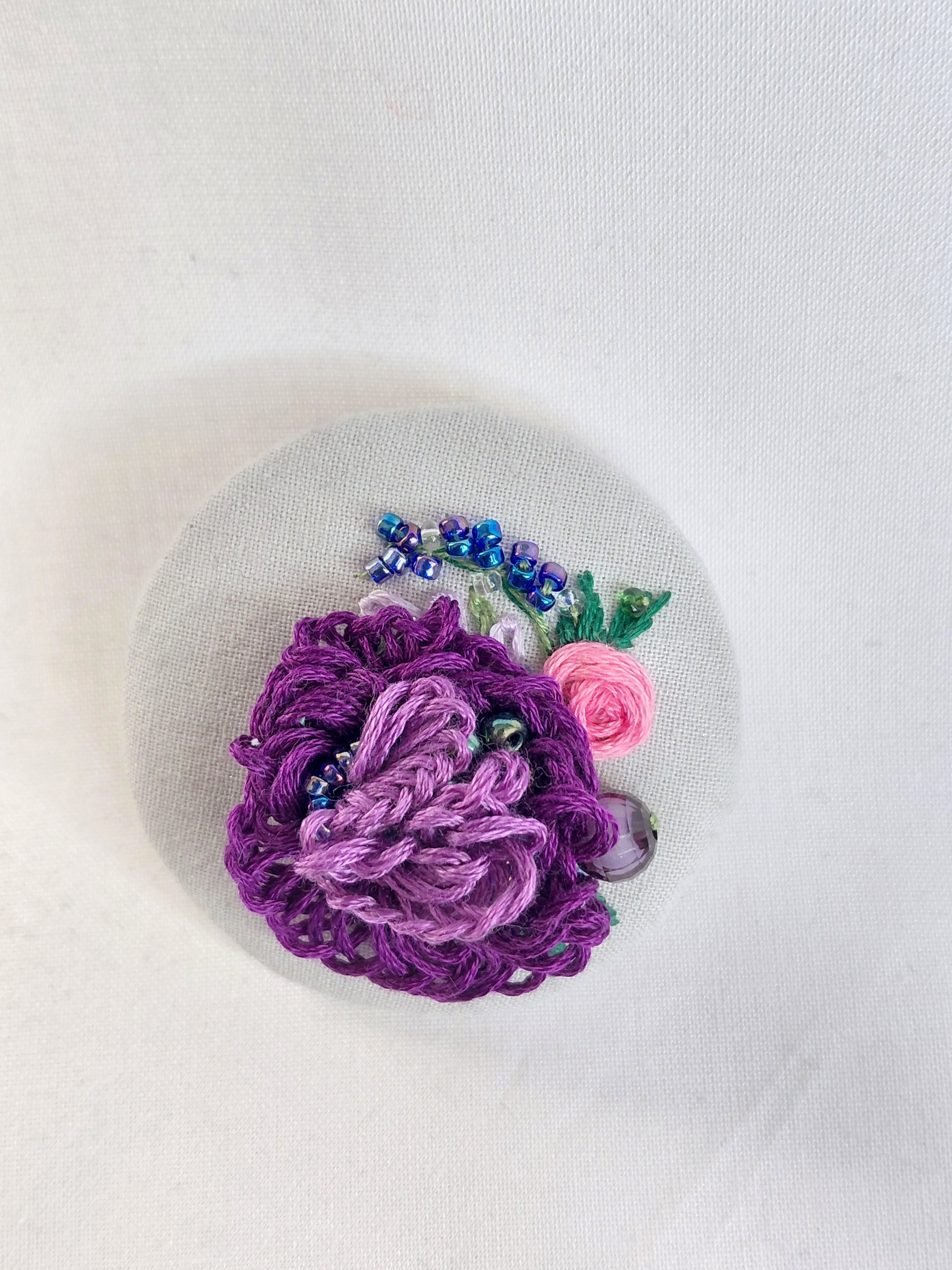 Decorative purple flower brooch on grey spec background