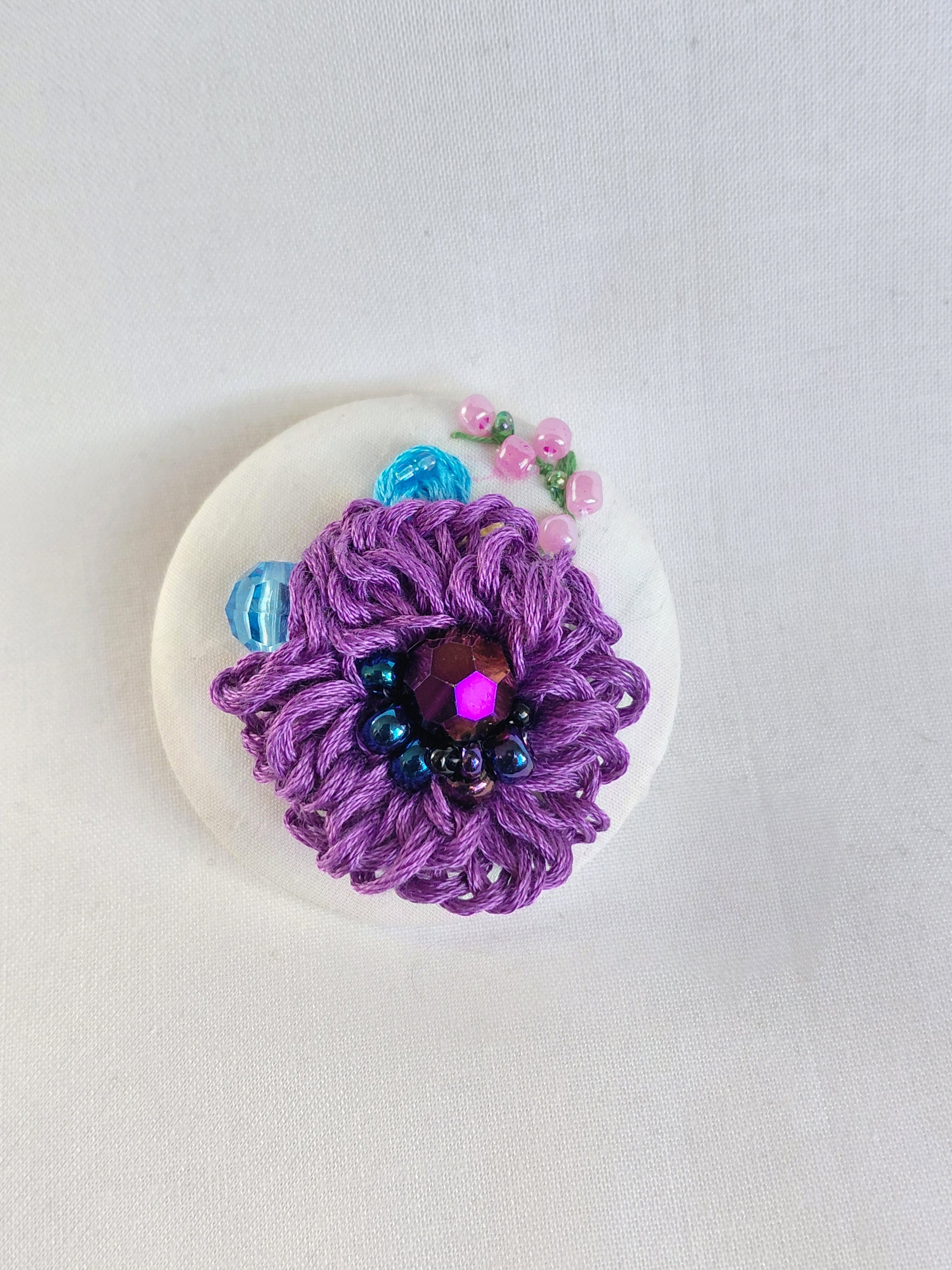 Decorative purple flower brooch on white background